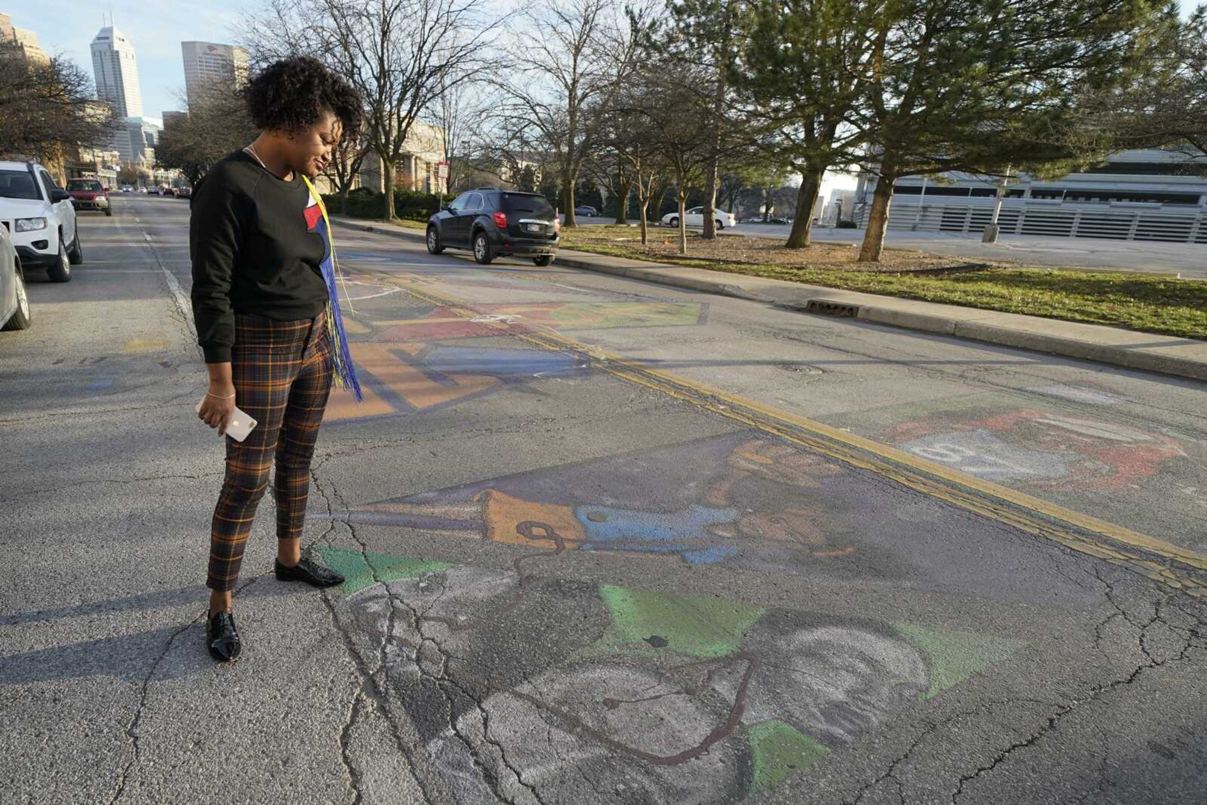 Malina Jeffers looks at the Black Lives Matter street mural stretching across Indiana Avenue on Thursday in Indianapolis. The mural is wearing down from traffic, and with winter will come weather damage and snow plows.