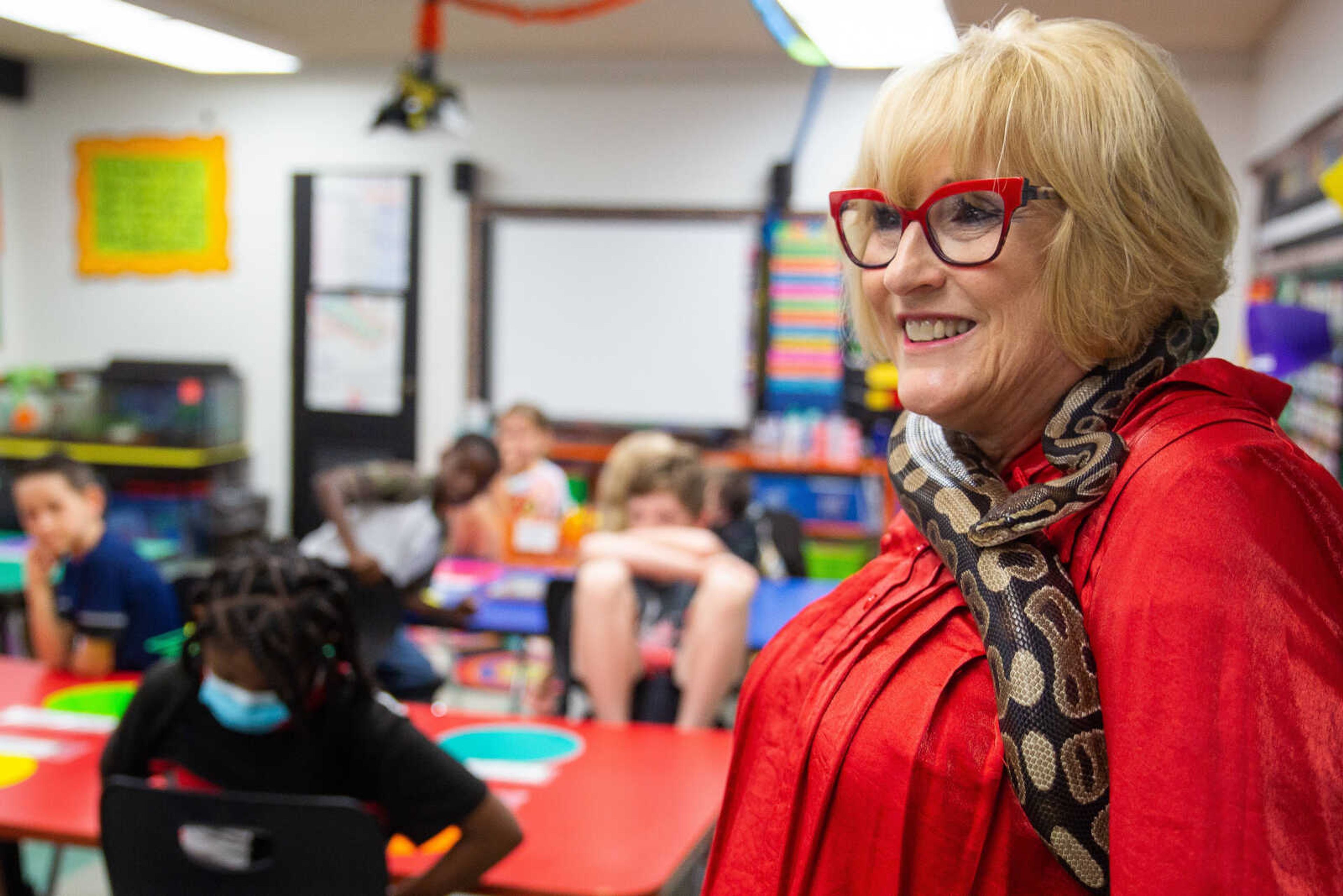 Mrs.&nbsp; Young smiles in front of her class as Monty the pet snake wraps himself around her neck.