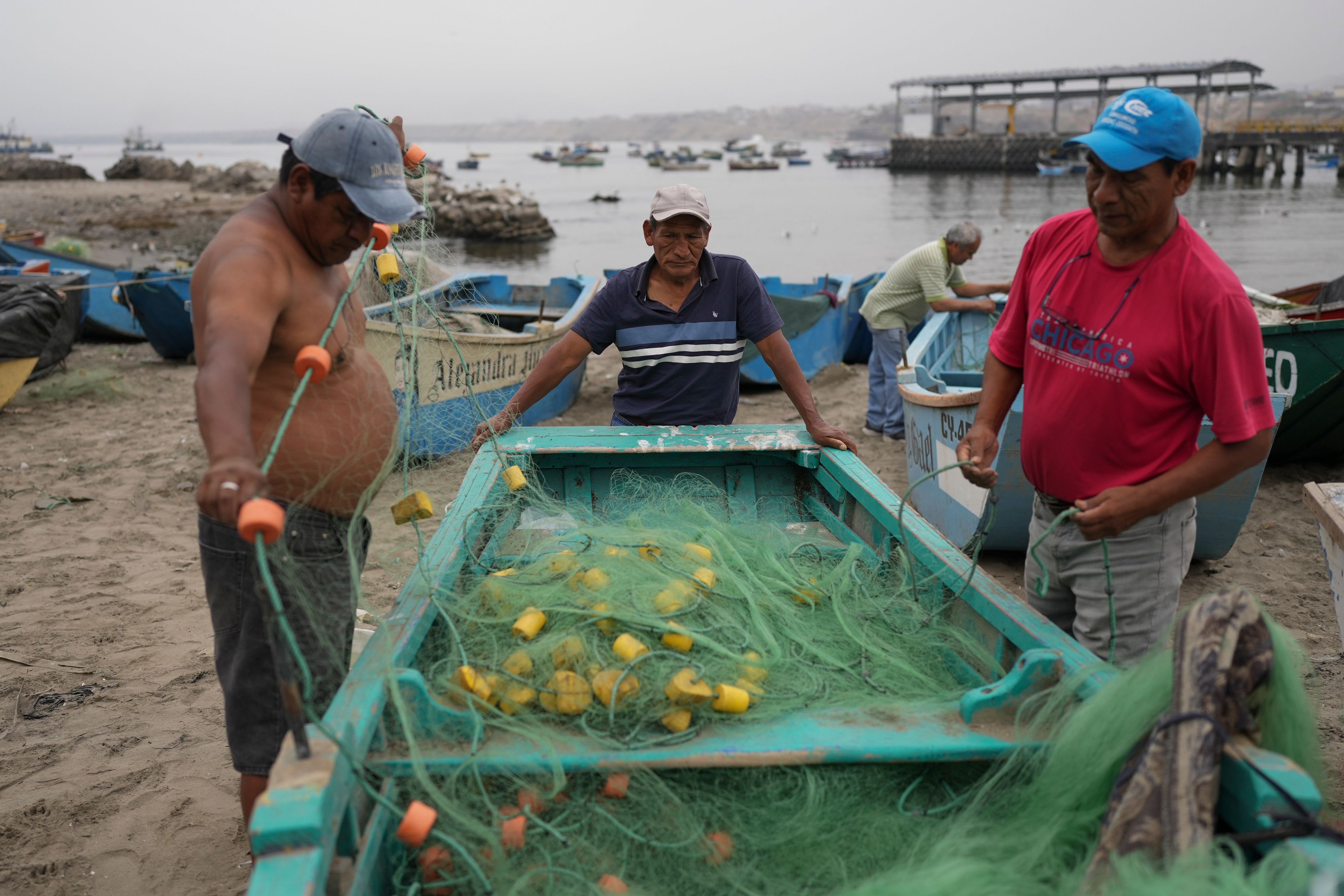 Fisherman Luis Castillo, center, and others prepare a net near a Chinese-funded port construction in Chancay, Peru, Tuesday, Nov. 12, 2024. (AP Photo/Silvia Izquierdo)