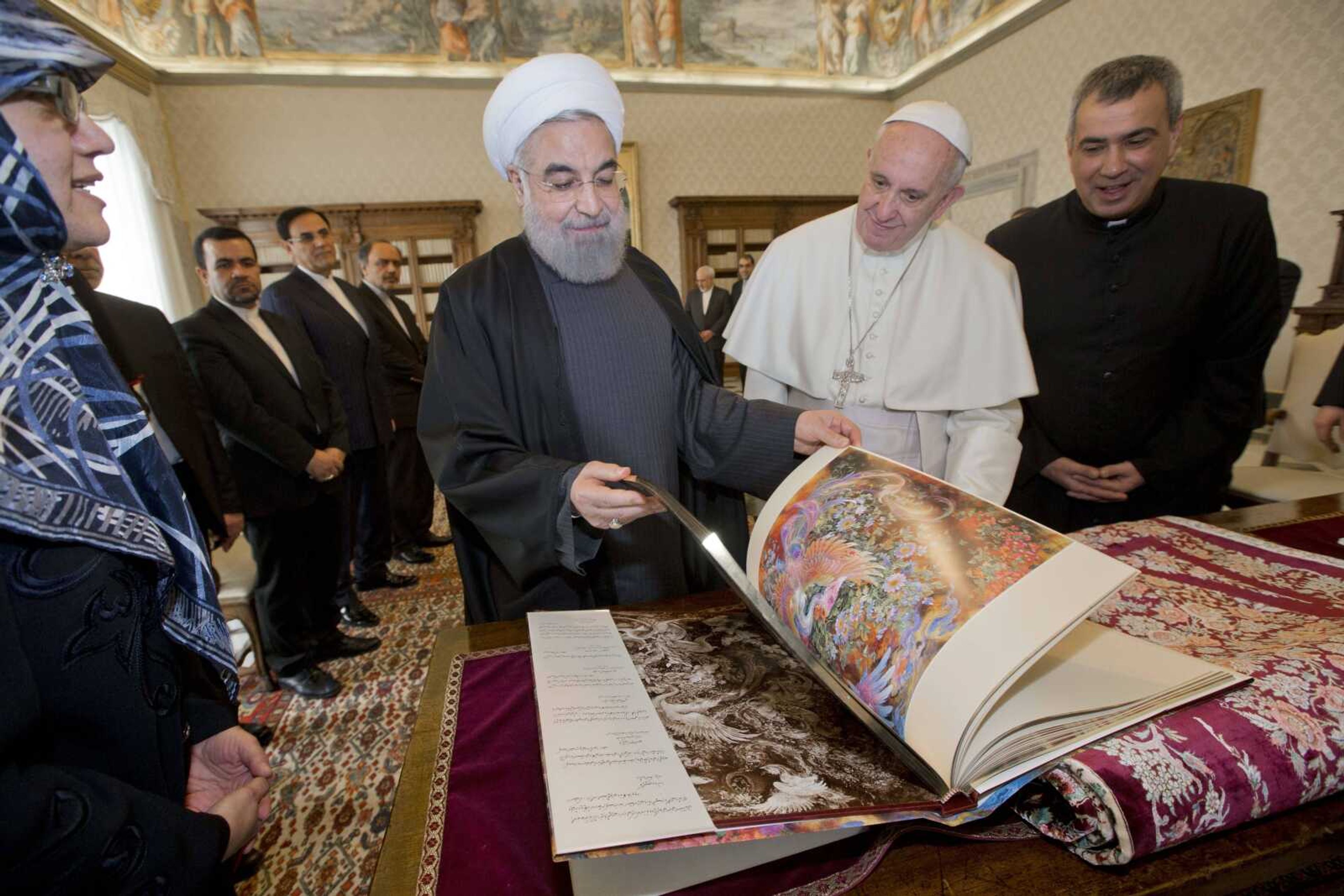 Iranian president Hassan Rouhani, left, leafs through a book he gave to Pope Francis as a gift during their private audience Tuesday at the Vatican.