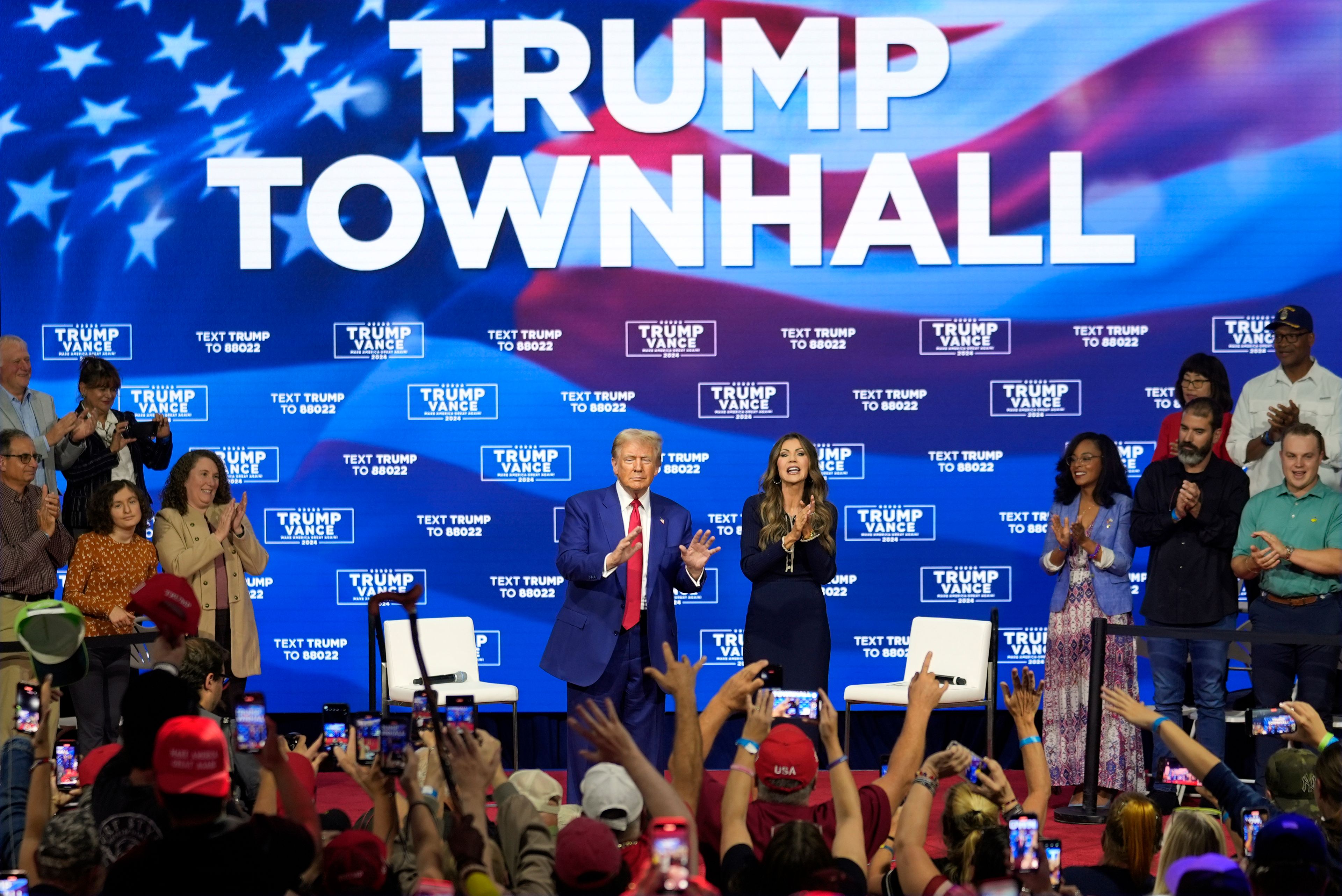 Republican presidential nominee former President Donald Trump gestures at a campaign town hall at the Greater Philadelphia Expo Center & Fairgrounds, Monday, Oct. 14, 2024, in Oaks, Pa., as moderator South Dakota Gov. Kristi Noem watches. (AP Photo/Matt Rourke)