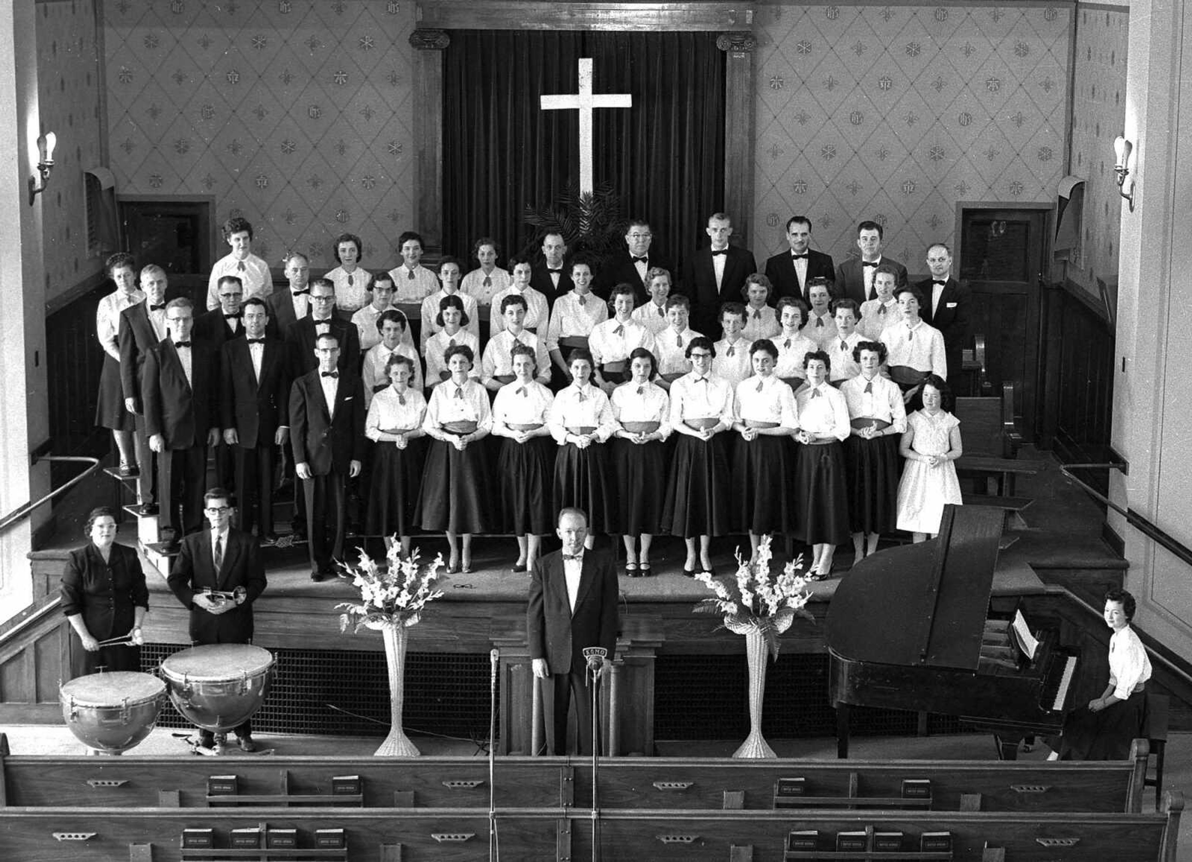 May 23, 1957 Southeast Missourian.
Cape Choraliers will present their sixth annual spring concert for the public at State College auditorium at 8 Friday night. The 44-voice chorus consists of the following members: Back row, left to right: Mrs. Lyall Carver, Miss Ruth Froemsdorf, Mrs. Emmett Young, Miss Carol Sparks, Mrs. Joe Francis Jr., R.G. Wagoner, Art Fischer, Gordon Mueller, Rudy Reimann, Harold Haas and Rev. George Michel; third row: Crawford McClue, R.P. Smith, Fred Scheerer, Mrs. Paul Wood, Miss Bonnie Barringer, Miss Pauline Galloway, Miss Mildred Wallace, Mrs. Earl Blackwell, Miss Mary Caldwell, Mrs. Kelley Gaines, Mrs. C.A. Bohnsack; second row: Dr. Paul Wood, Willard Adams, Rev. Guy Steele, Mrs. Oscar Kasten, Mrs. Martha Hunt, Miss Catherine Langley, Miss Jeannette Vandeven, Miss Dorothy Weber, Mrs. Howard Bock, Mrs. Bob Lemmons, Mrs. Thelvan Rickard, Mrs. Guy Steele: front row: Henry Creighton, Mrs. Charles James, Mrs. Emil Werner, Mrs. Glenn Smith, Mrs. Joe Blackwell, Mrs. Joe Davis, Mrs. Pat Stroder, Mrs. Leo Boren, Mrs. John Hill Jr., Mrs. D.J. Barks, and Gloria Sue Palsgrove, a guest accompanist. In the foreground are pictured Miss Peggy Head and Don Werner guest musicians, who accompany the chorus for the “Song of Easter” selection; Director Jack Palsgrove, and Mrs. Betty Sue Palsgrove at the piano. (G.D. Fronabarger/Southeast Missourian archive)