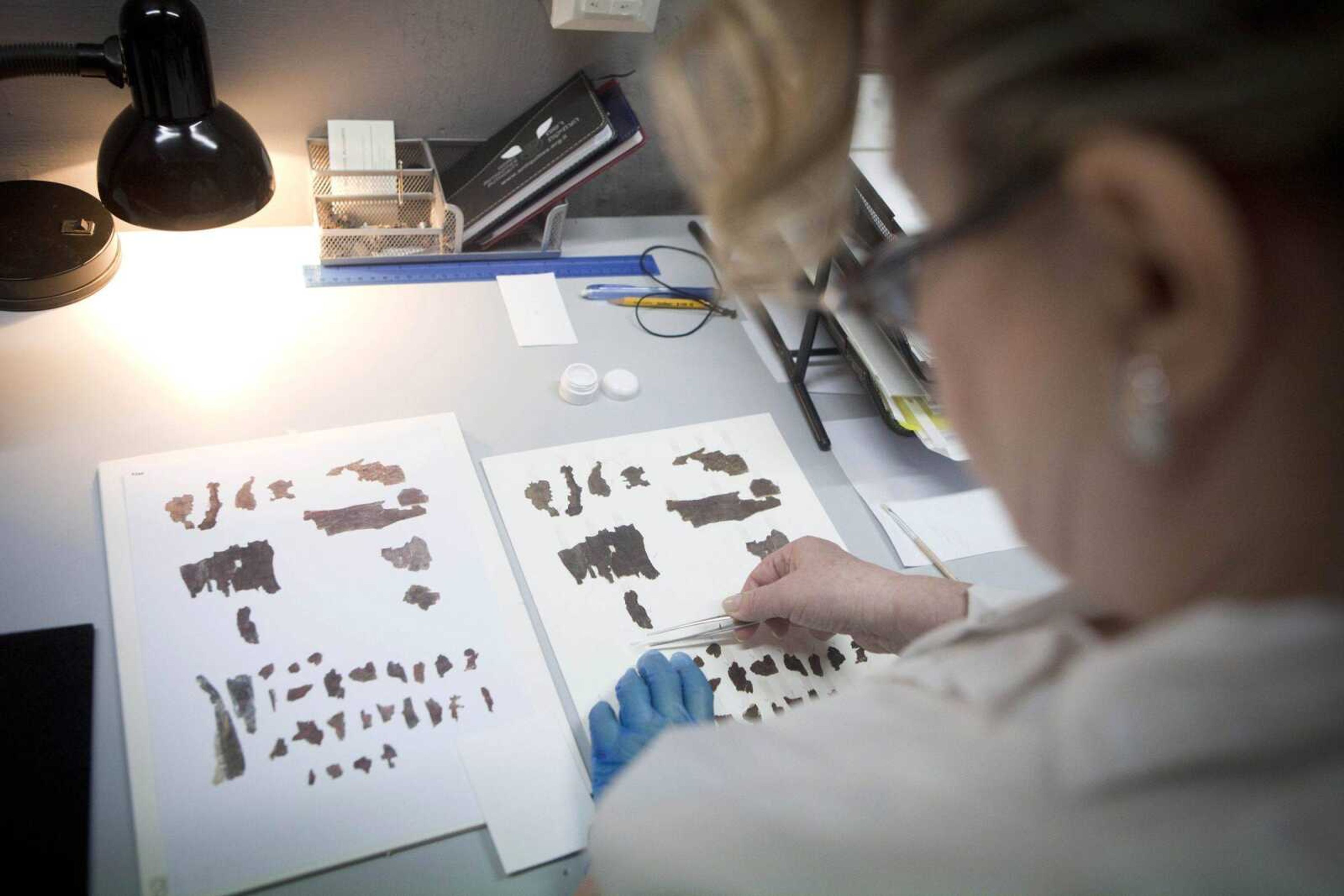 An Israel Antiquities Authority employee works on fragments of the Dead Sea Scrolls on May 10 in Jerusalem. Written mostly on animal skin parchment about 2,000 years ago, the manuscripts are the earliest copies of the Hebrew Bible ever found. (Dan Balilty ~ Associated Press)