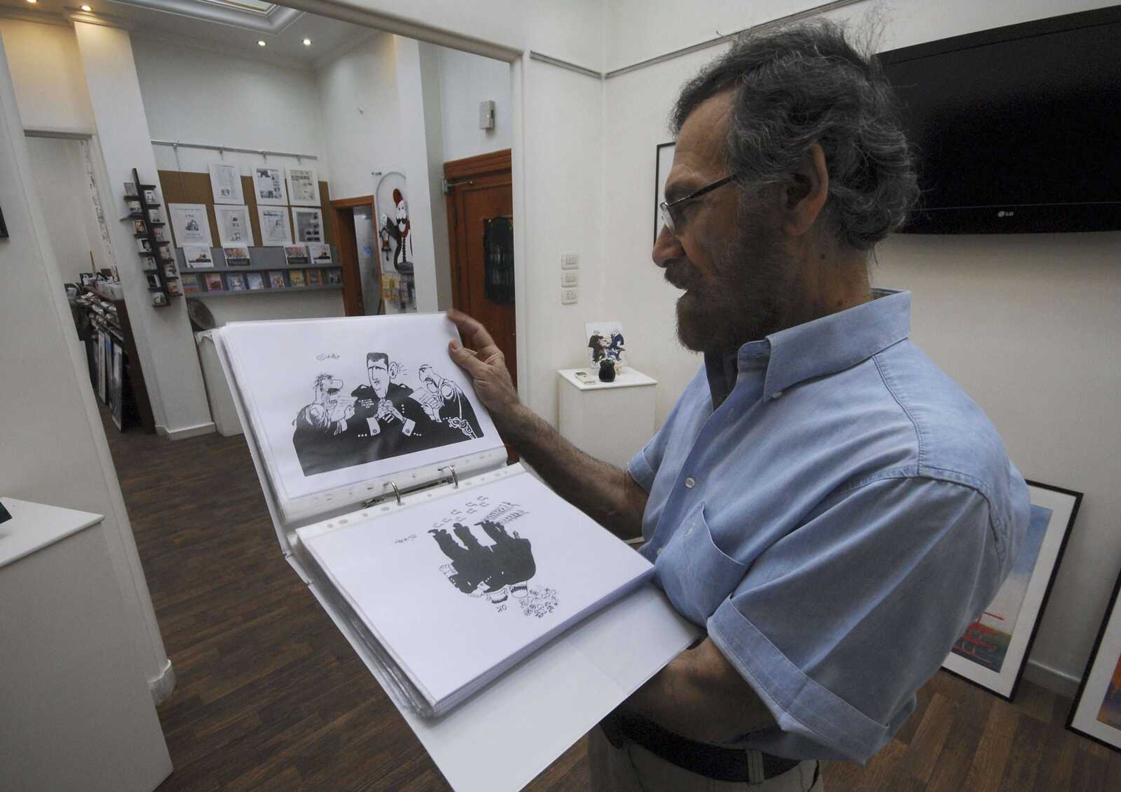 Syrian cartoonist Ali Ferzat shows his work in his atelier Aug. 14 in Damascus, Syria. Syrian security forces attacked Ferzat early Thursday in Damascus and left him bleeding along the side of a road, human rights activists said. (Muzaffar Salman ~ Associated Press)