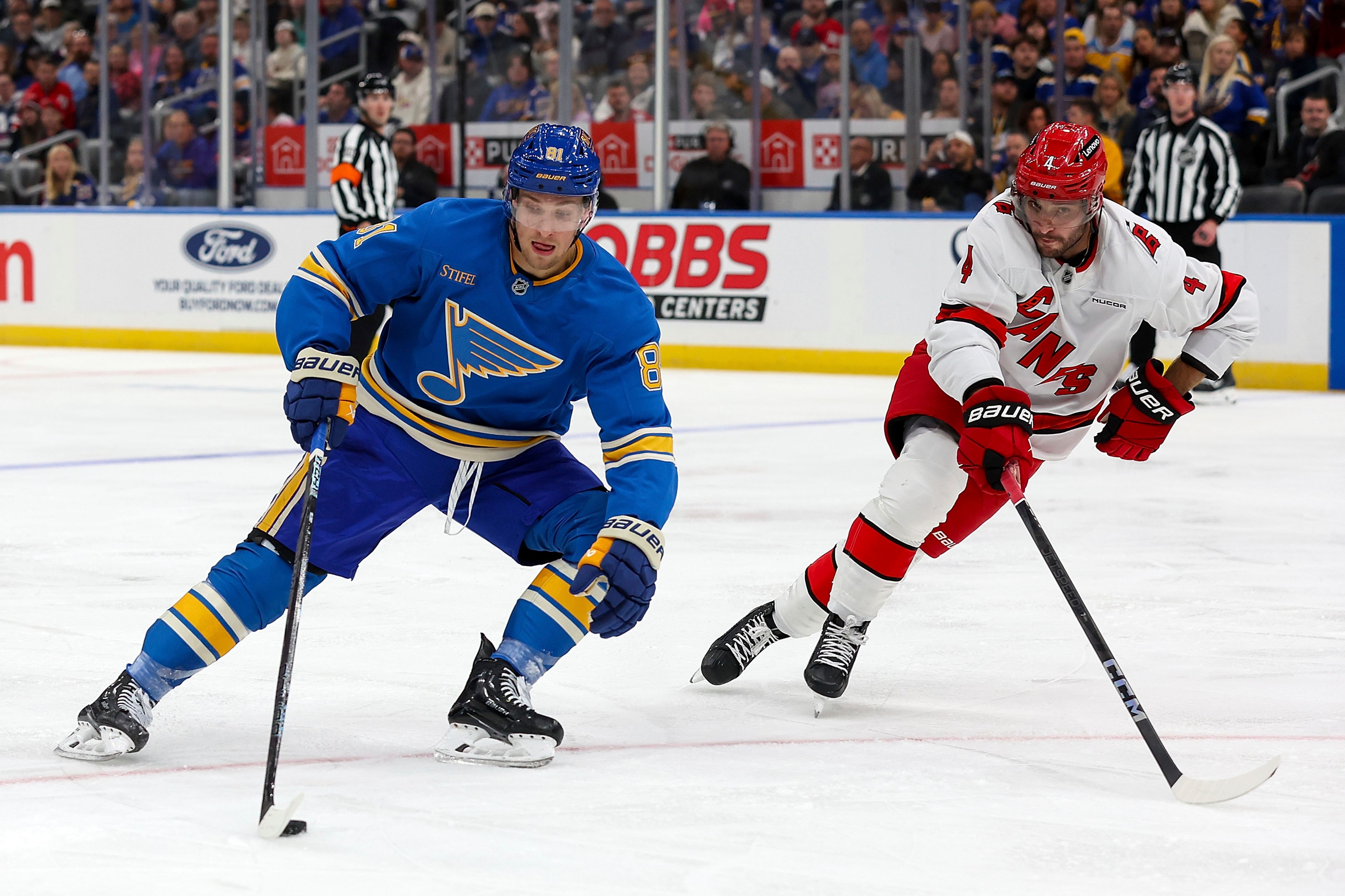 St. Louis Blues' Dylan Holloway (81) controls the puck while under pressure from Carolina Hurricanes' Shayne Gostisbehere (4) during the second period of an NHL hockey game Saturday, Oct. 19, 2024, in St. Louis. (AP Photo/Scott Kane)