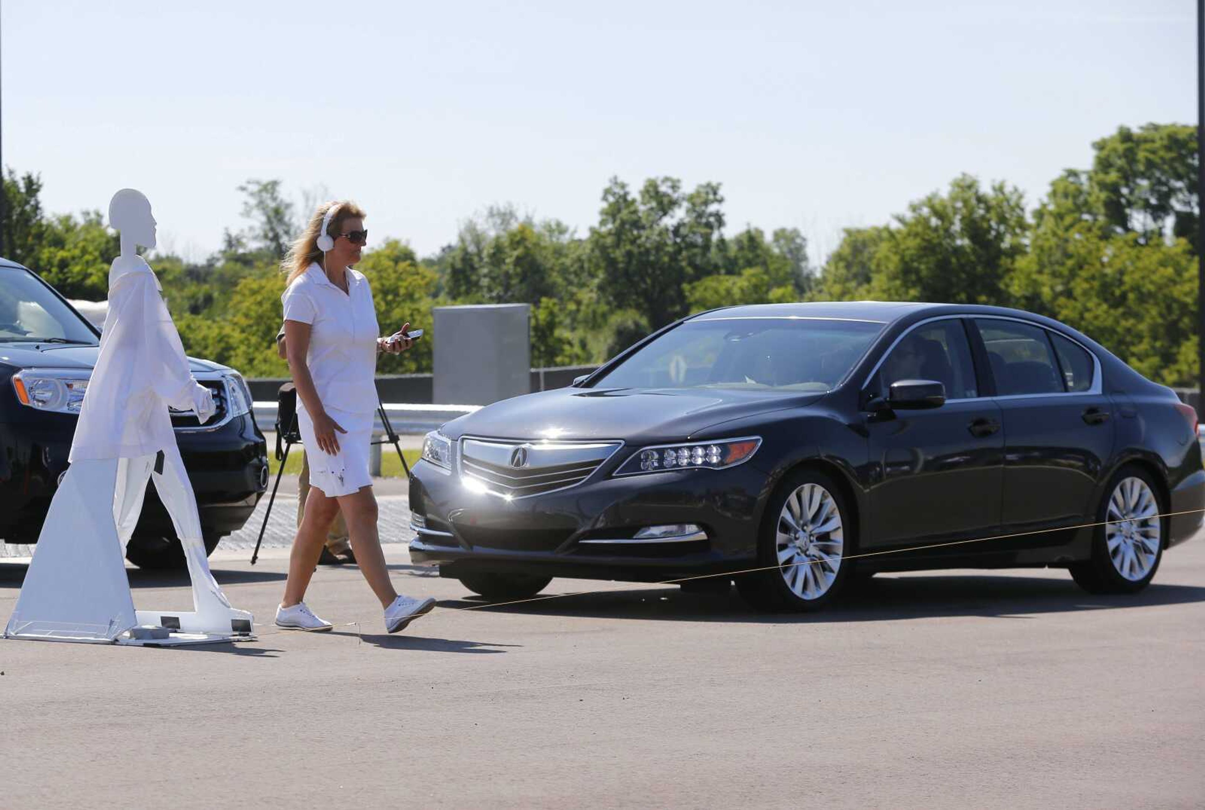 A pedestrian crosses in front of a car as part of an autonomous-vehicle demonstration at the University of Michigan campus in Ann Arbor.