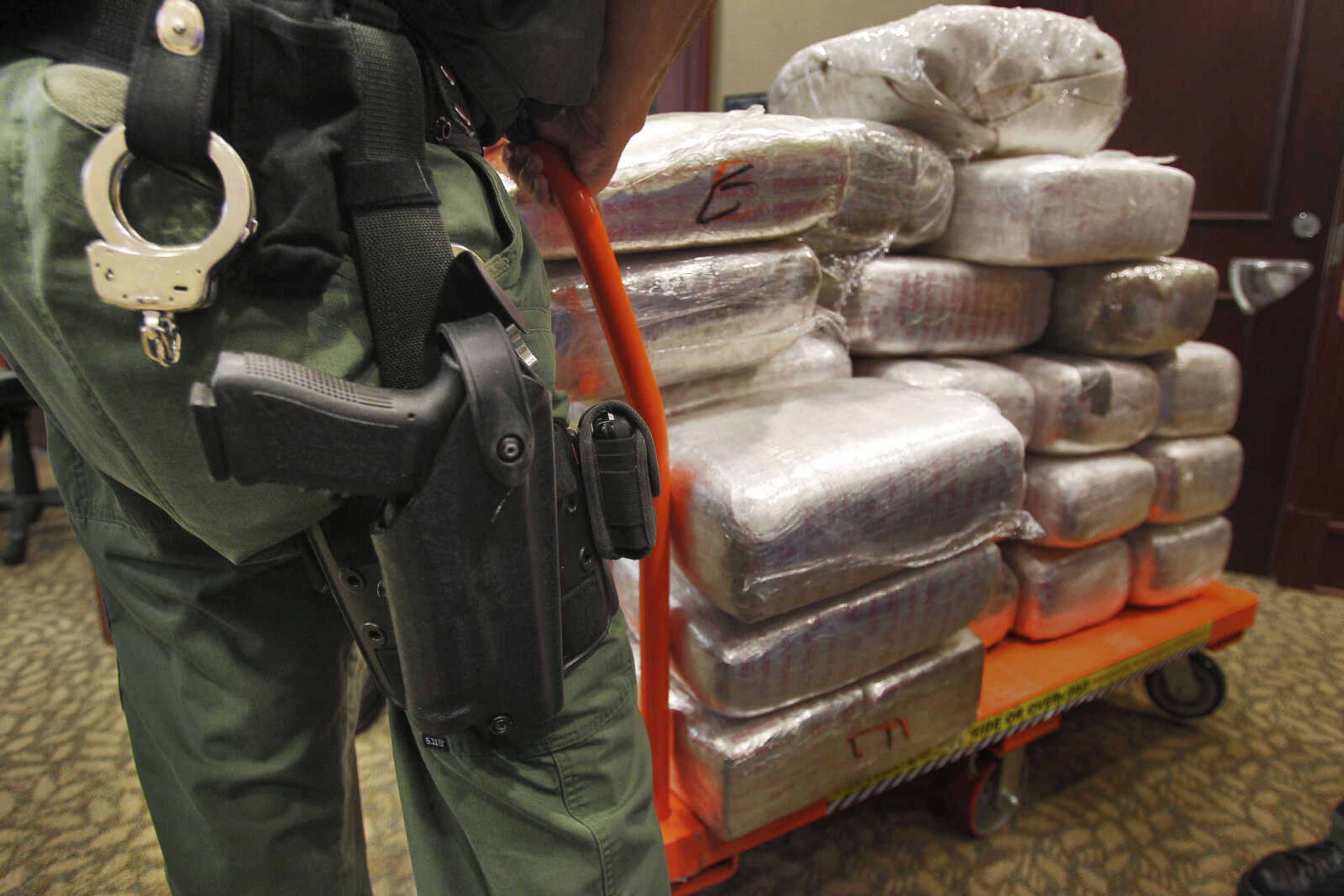 FILE - In this Nov. 4, 2010 file photo, bales of marijuana are wheeled out at a news conference in Jonesboro, Ga. Forty-five people were arrested 45 people along with cash, guns and more than two tons of drugs as part of an investigation by federal and local law enforcement into the Atlanta-area U.S. distribution hub of Mexico's La Familia drug cartel. Drug cartels have long been the nation's No. 1 supplier of illegal drugs, but in the past, their operatives rarely ventured beyond the border. A wide-ranging Associated Press review of federal court cases and government drug-enforcement data, plus interviews with many top law enforcement officials, indicate the groups have begun deploying agents from their inner circles to the U.S. (AP Photo/Atlanta Journal-Constitution, John Spink)