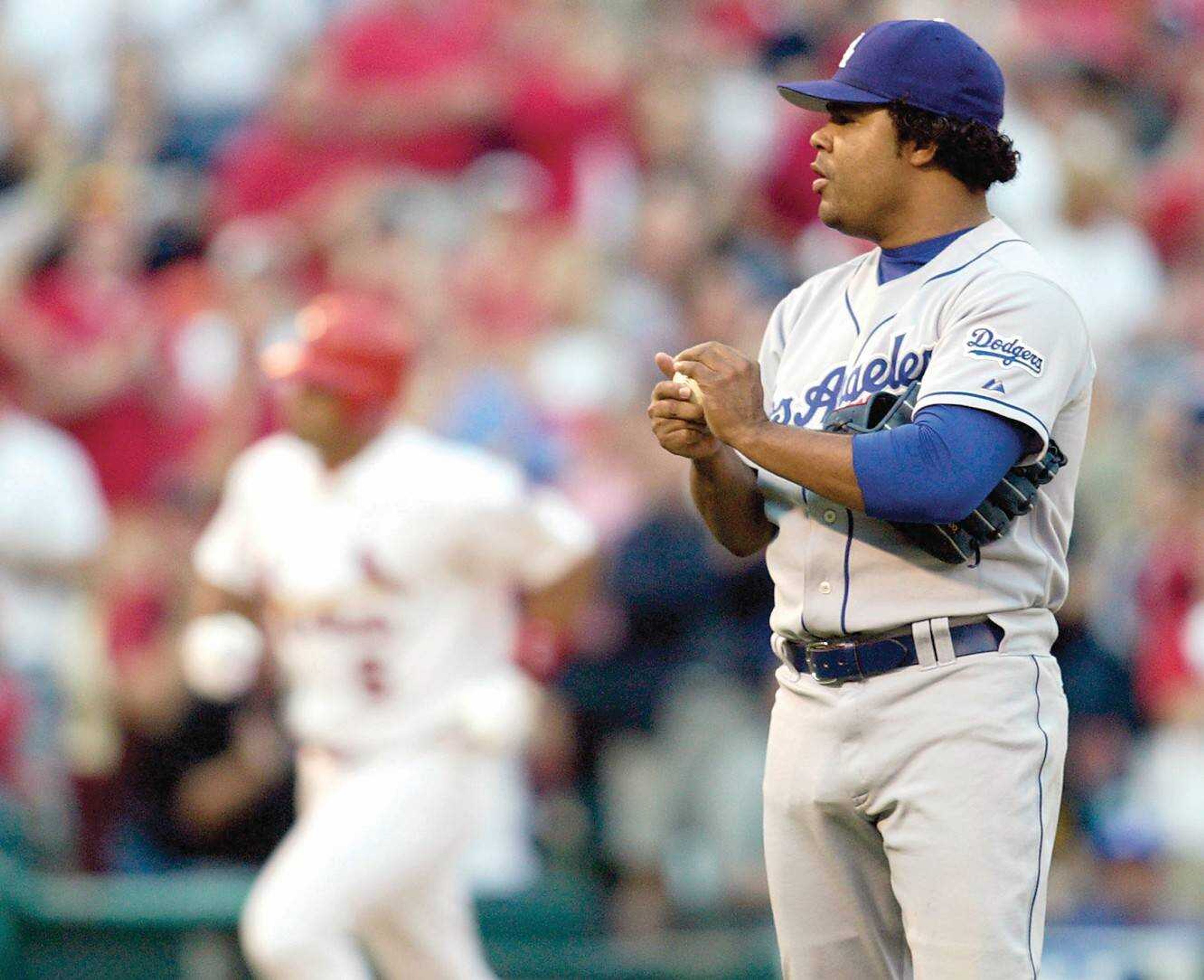 Dodgers pitcher Odalis Perez rubbed up a new ball, as the Cardinals' Albert Pujols circled the bases after hitting a solo home run in the first inning Monday at Busch Stadium. Pujols later added a three-run home run off Perez.