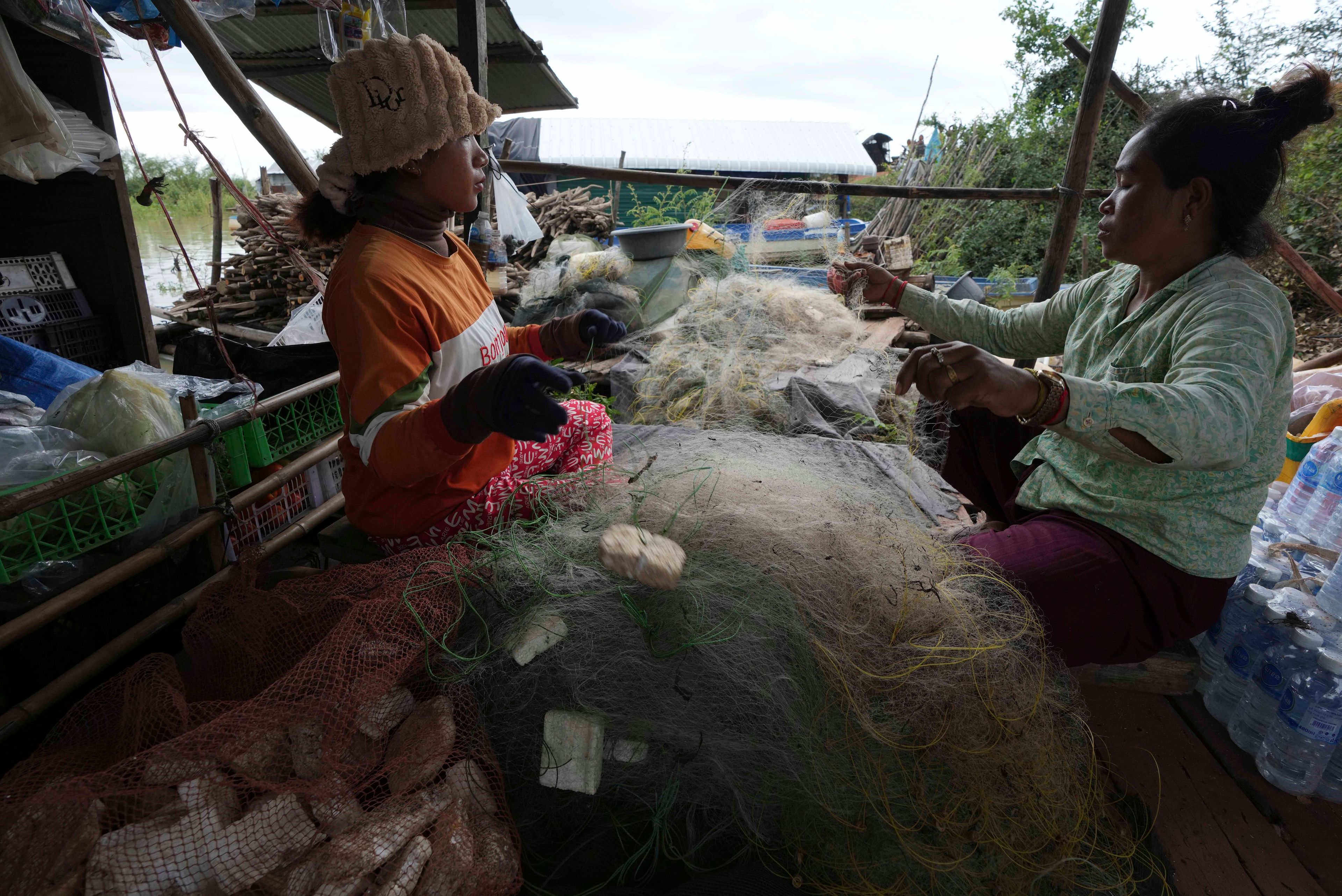 Locals fix their fishing nets at a floating village by the Tonle Sap in Kampong Chhnang province, Cambodia, Thursday, Aug. 1, 2024, (AP Photo/Heng Sinith)