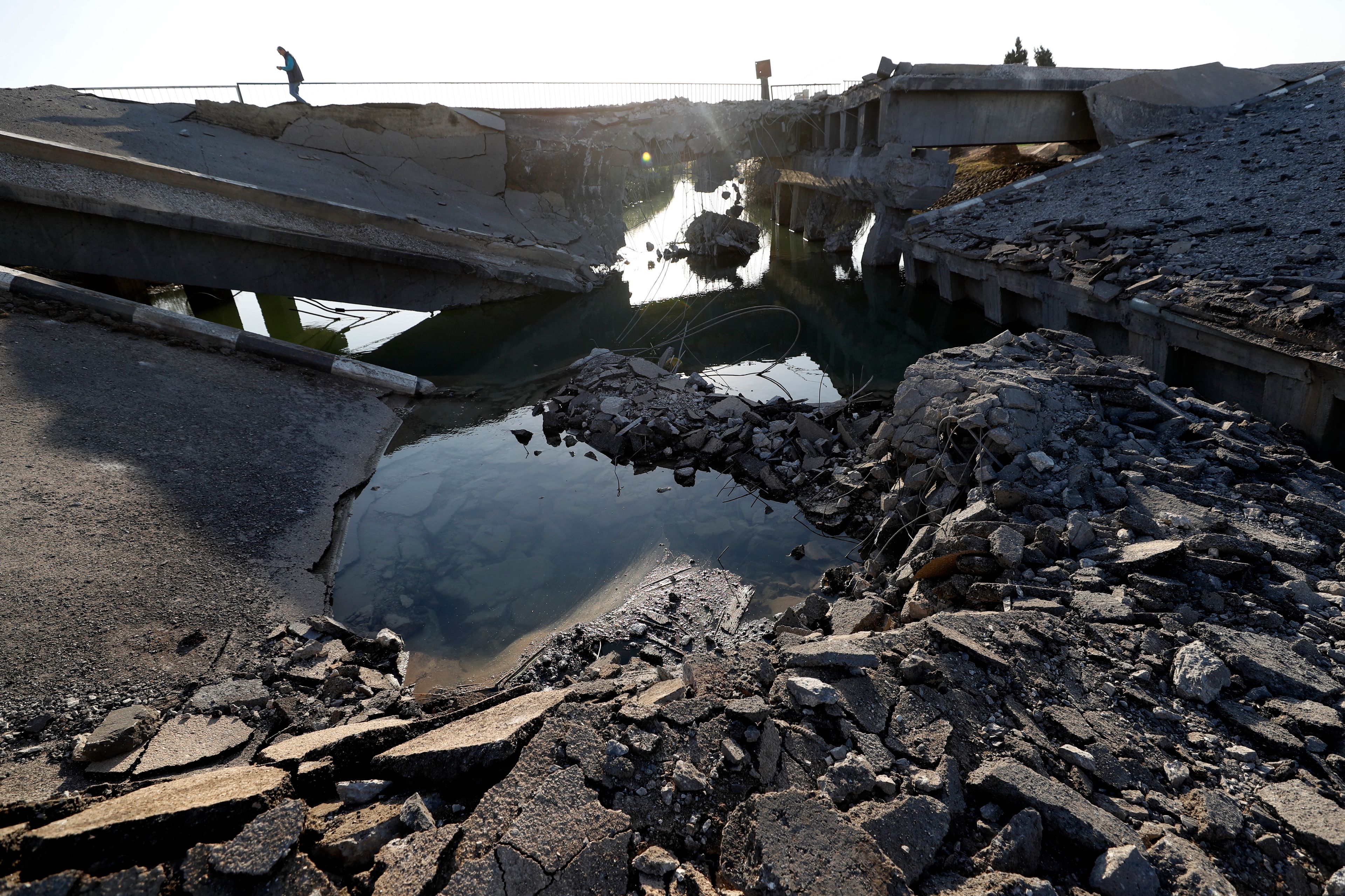 A Syrian man passes by a bridge that links to Lebanon which was destroyed on Oct. 24 by an Israeli airstrike, in Qusair, Syria, Sunday, Oct. 27, 2024. (AP Photo/Omar Sanadiki)