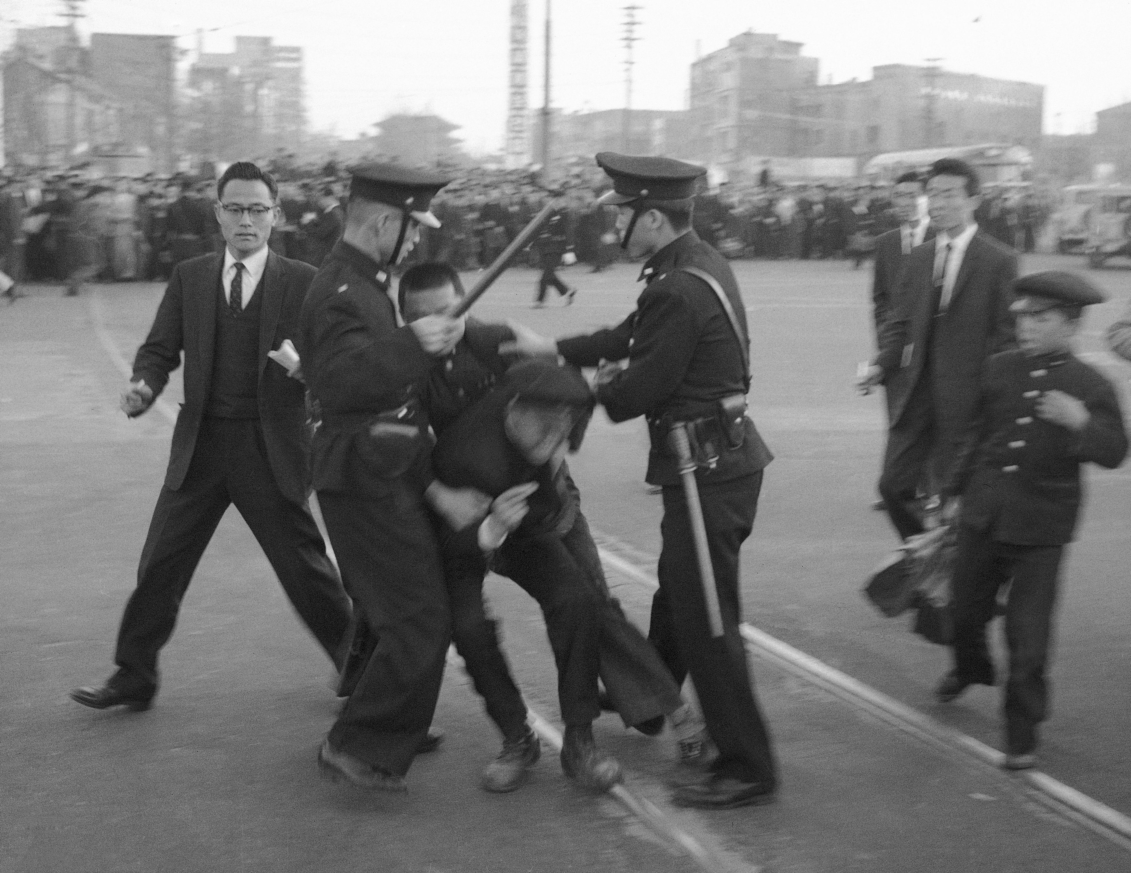 FILE- Two policemen flank demonstrators in Seoul, South Korea on April 18, 1960 using clubs to break up a riot protesting the March 15 presidential election. Demonstrations continued and on April 19 in the South Korean capital martial law was declared. (AP Photo, File)