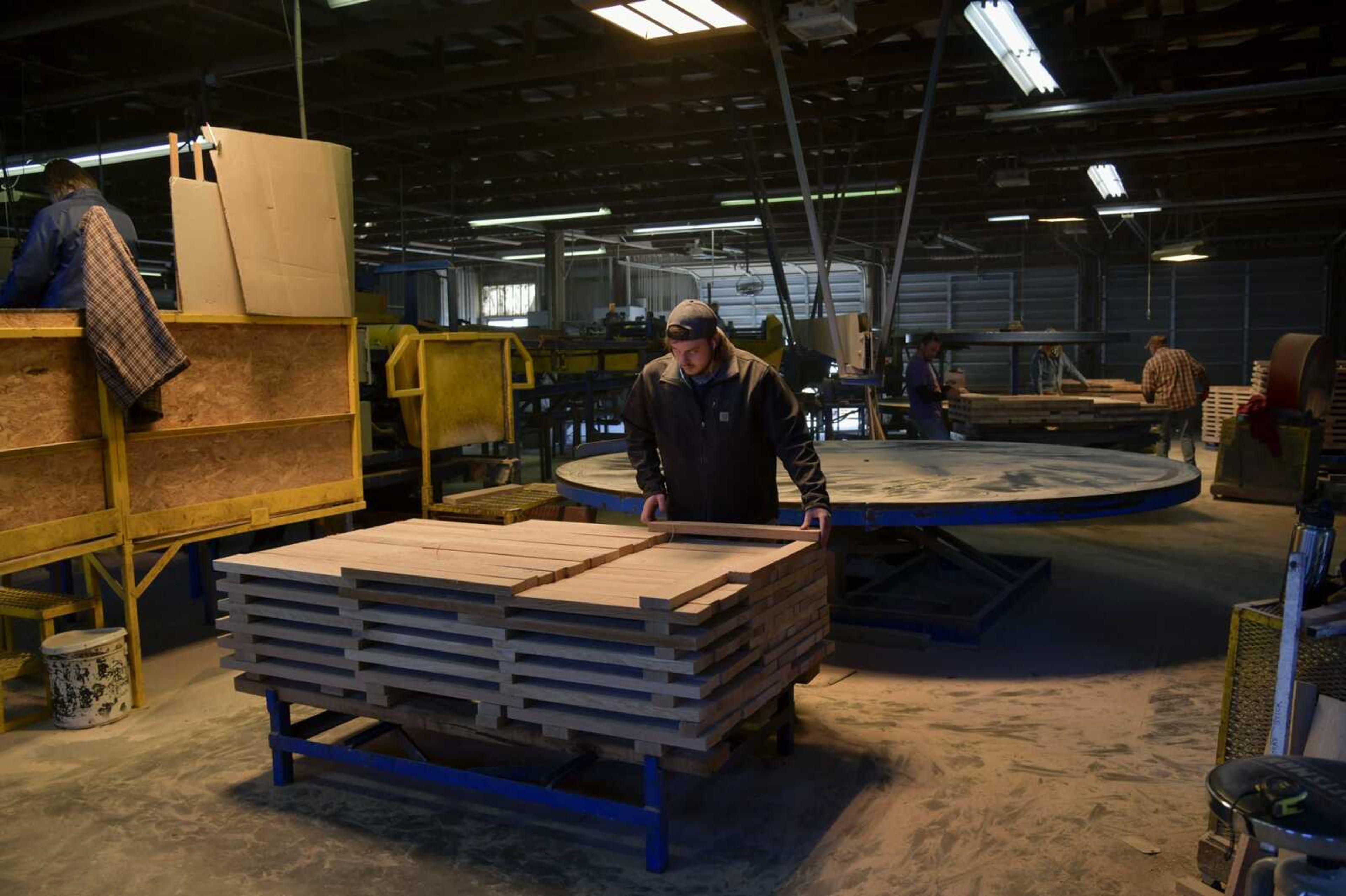 An employee carefully stacks a stave that came from the machine behind him so it can be stored and shipped out Thursday at Perryville Stave Co. in Perryville, Missouri.