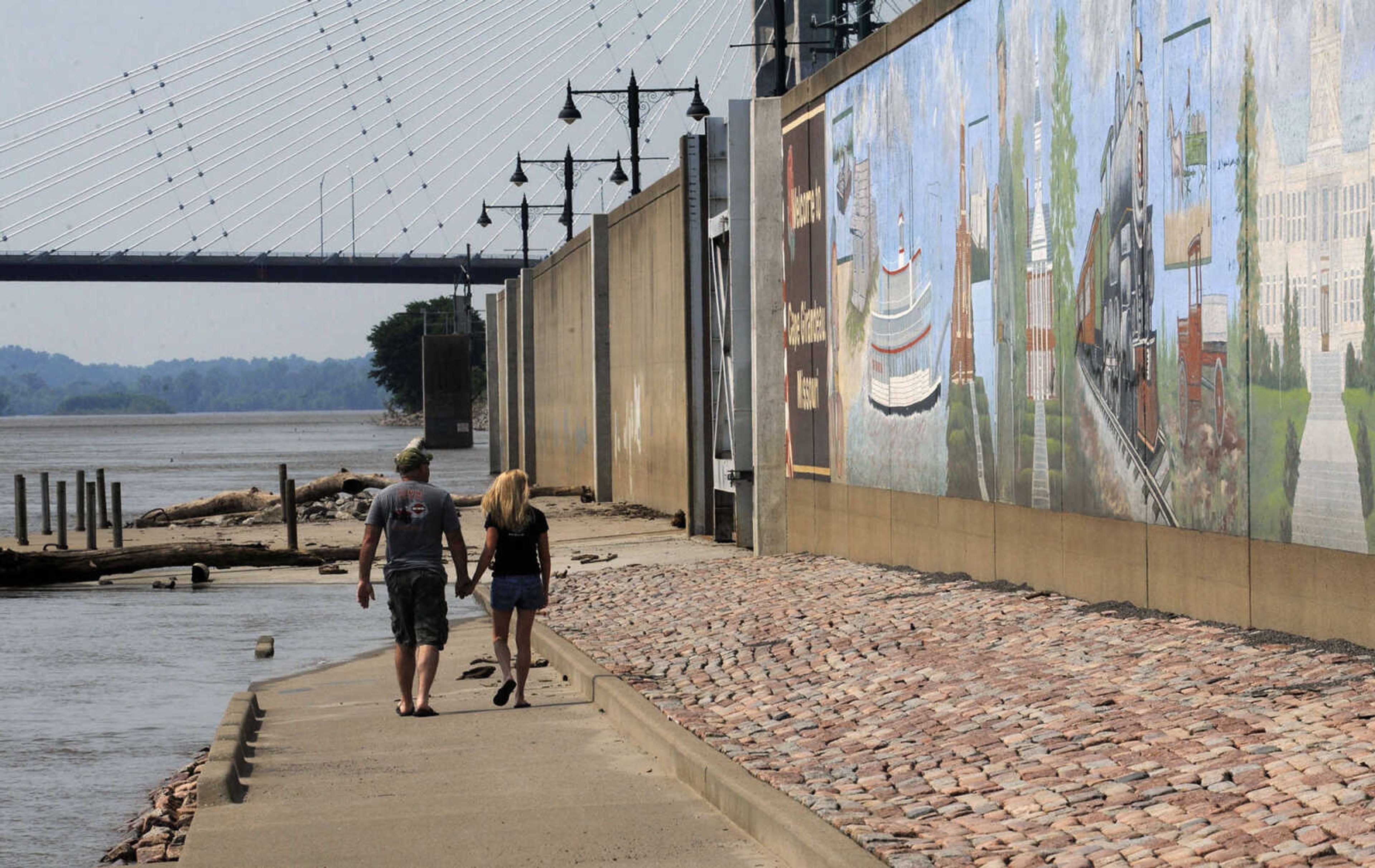 A couple strolls along the riverfront near the Themis Street floodgate which is open again.