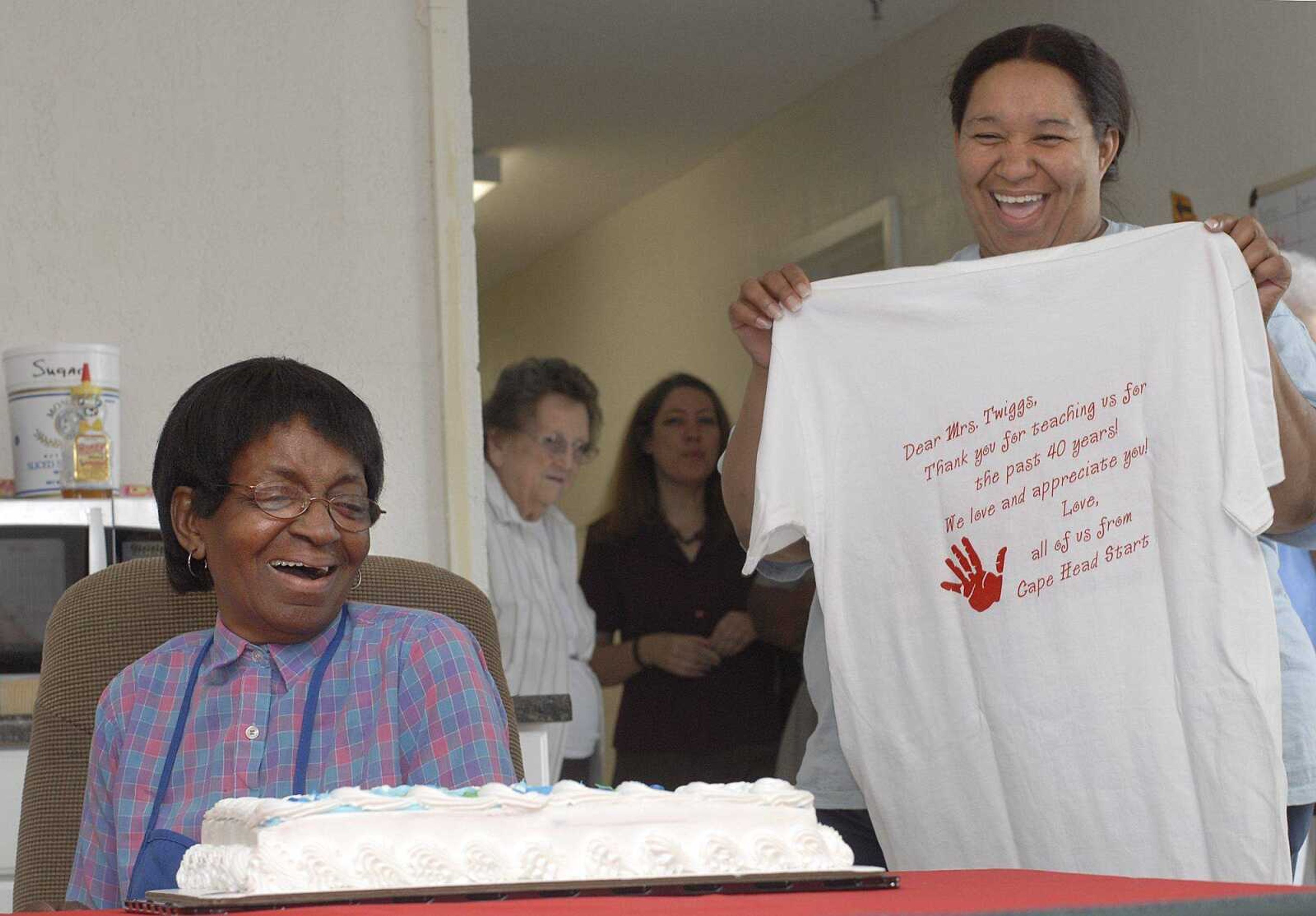 Leola Twiggs, left, reacts with surprise at a reception honoring her 40 years with Head Start. Sandra Long, a family advocate, presents her with a special T-shirt. (Fred Lynch)