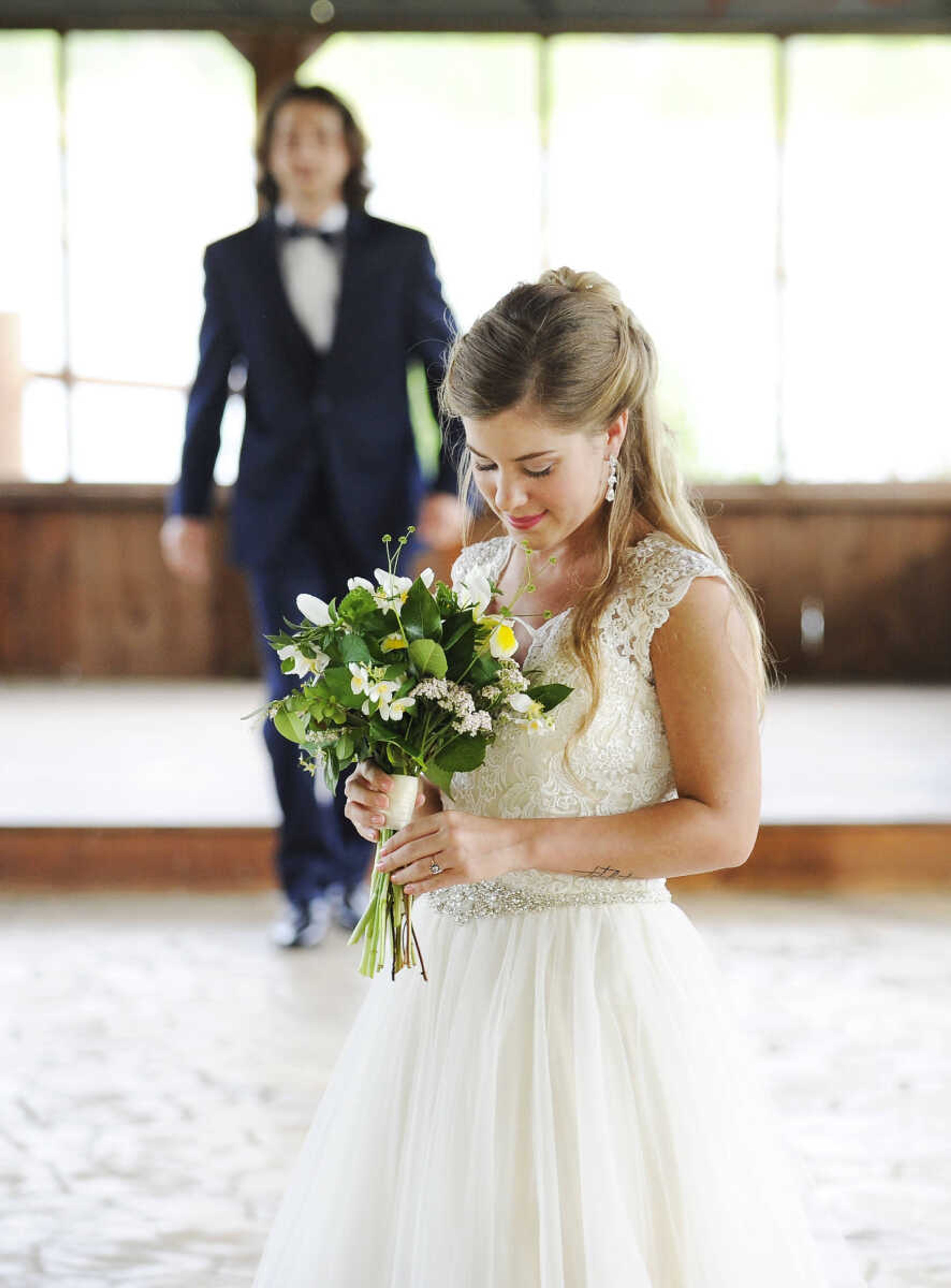 On Lydia: Allure Bridals gown in ivory with tulle skirt, lace bodice, beaded waste and button-back closure. Drop earrings by Jim Ball. All available at Joy's Bridal in Sikeston, Missouri. 

On Evan: Navy Sterling slim fit wedding suit by Michael Kors with navy plaid bow tie. Provided by Jim's Formal Wear and available at Garber's Men's Wear in Cape Girardeau.