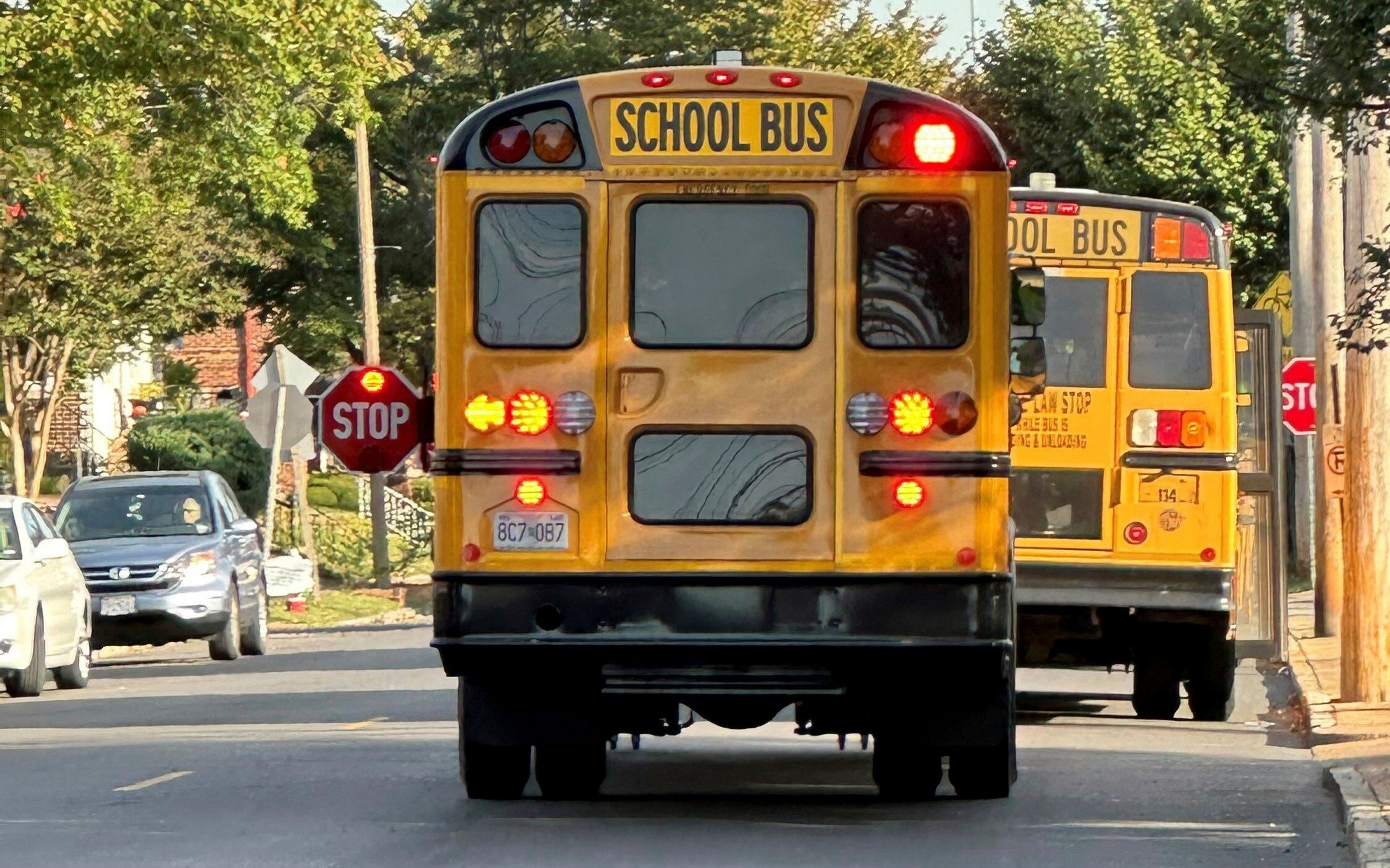 An unmarked school bus dropped students off at Shaw Visual and Performing Arts elementary school, a St. Louis Public school, on Monday, Oct. 14, 2024, in St. Louis. School buses are required by state law to have "STATE LAW: STOP WHILE BUS IS LOADING AND UNLOADING" in black letters on the back. (Blythe Bernhard/St. Louis Post-Dispatch via AP)