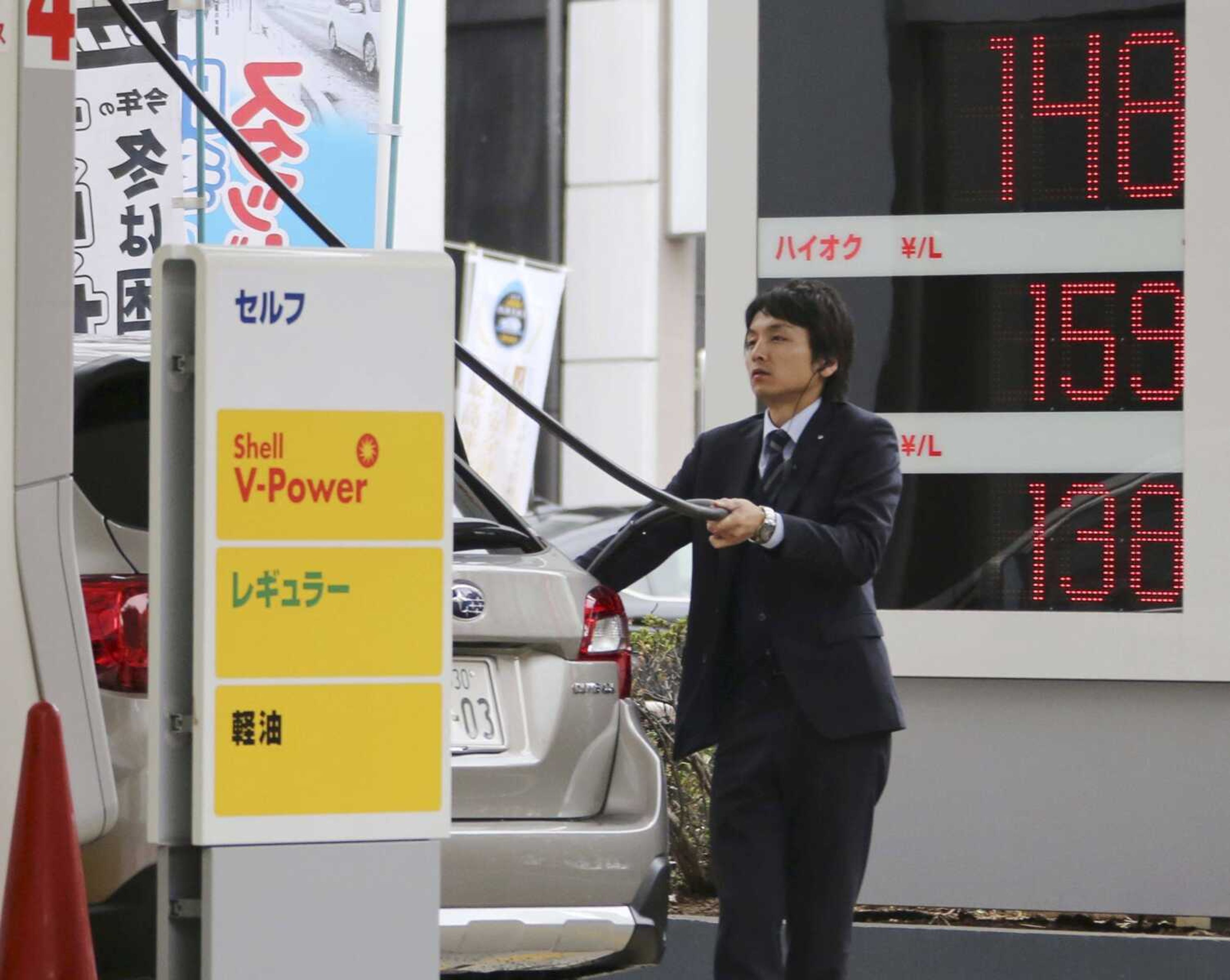 A man puts gas in his car at a Shell station Friday with the electric indicator showing a liter of regular gas priced at 148 yen, or $1.25, per liter in Tokyo. (Koji Sasahara ~ Associated Press)