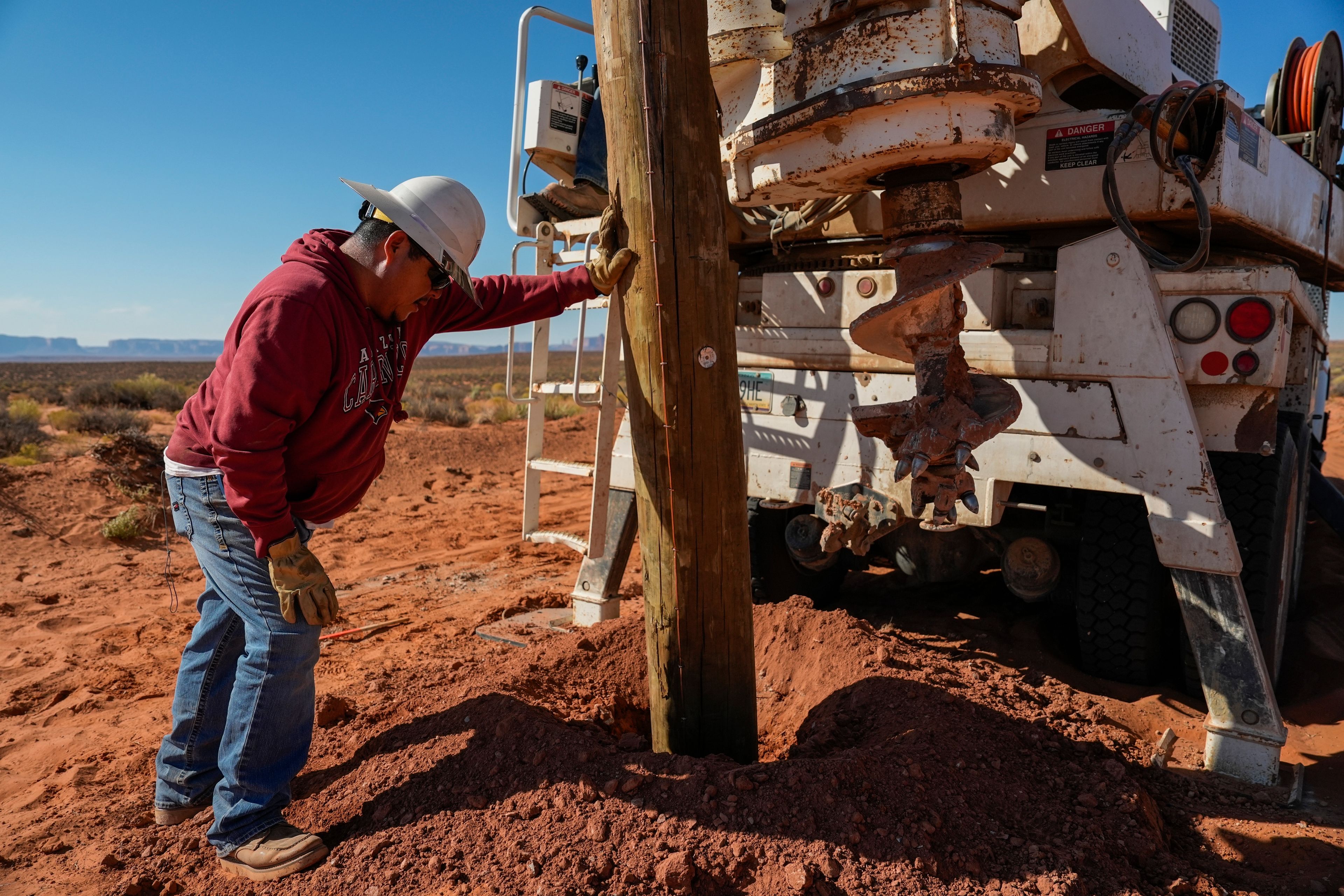 Ryan Smith, left, a foreman with the Navajo Tribal Utility Authority, checks the depth of a power pole during construction, Wednesday, Oct. 9, 2024, on the Navajo Nation in Halchita, Utah. (AP Photo/Joshua A. Bickel)