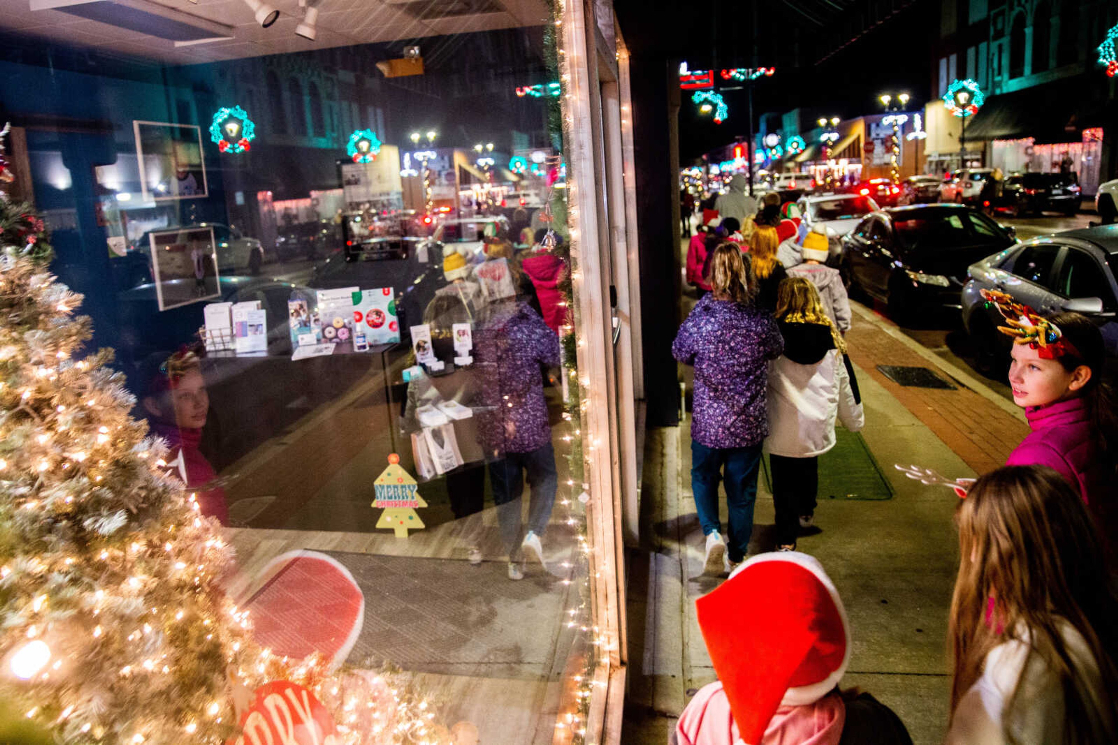 Fourth grade choir students look into shop windows as they walk down Main Street caroling inside and outside of businesses&nbsp;on Friday, Dec. 2 in downtown Cape Girardeau.