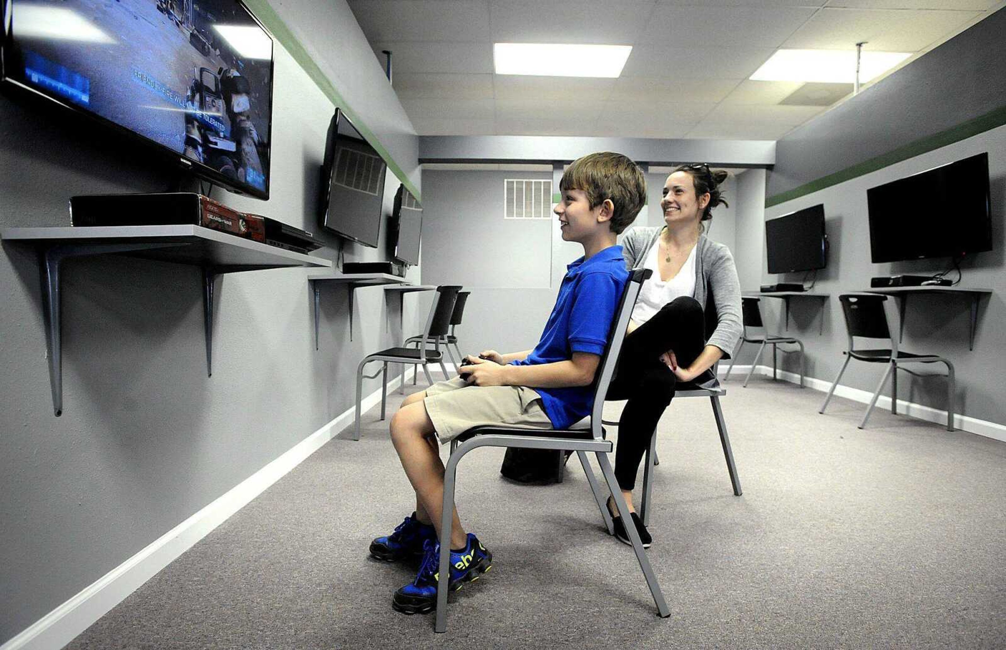 Emily Hoehn watches her son, Adrik Tsymberov, while he plays an Xbox 360 game on Friday at Gaming Grounds in Cape Girardeau. Tsymberov traded in some video games at the store before sampling two Xbox 360 games. (Laura Simon)