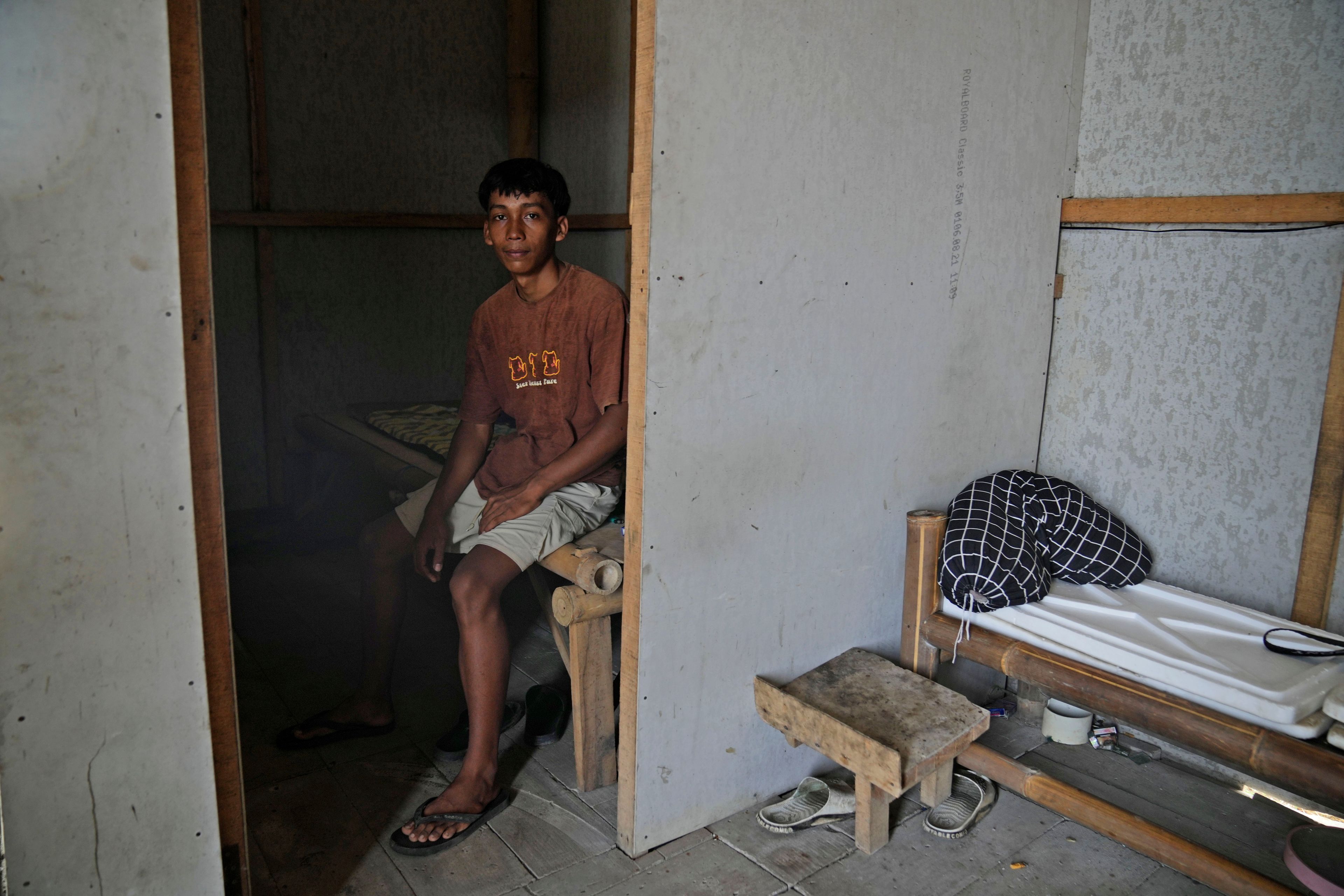 Farm worker Dias Yudho Prihantoro sits on his bed inside the hut where he and his brother stay during their work shifts at a shrimp farm in Kebumen, Central Java, Indonesia, Tuesday, Sept. 24, 2024. (AP Photo/Dita Alangkara)