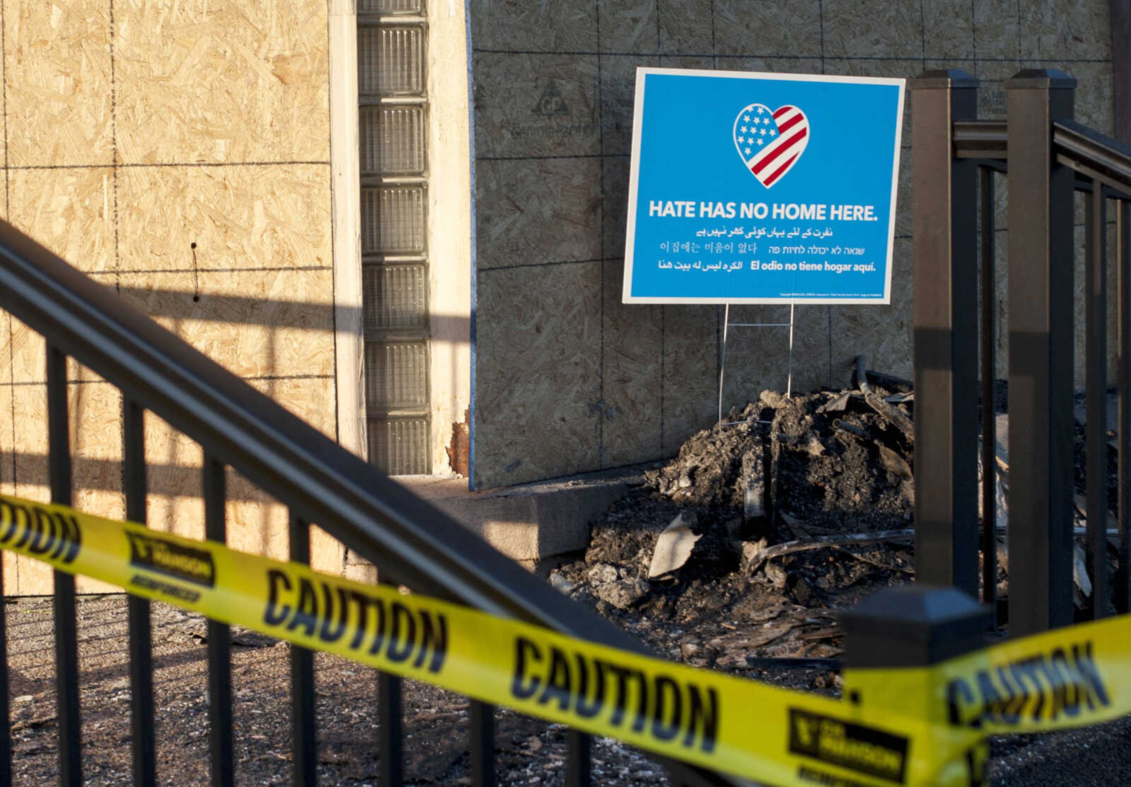 A sign bearing a message of unity stands above a pile of ashes and burnt debris Sunday, April 26, 2020, at the Islamic Center of Cape in Cape Girardeau.