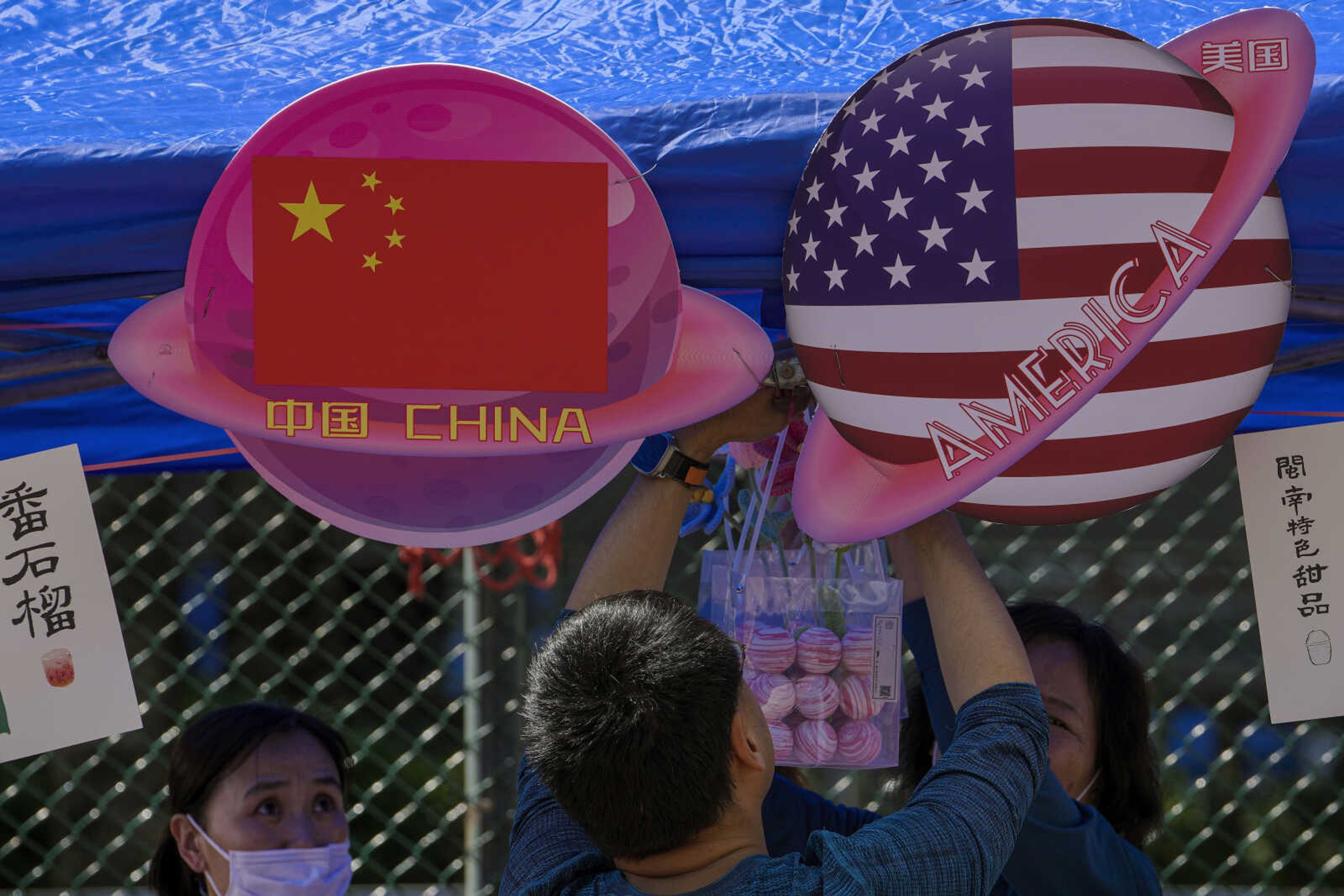 A vendor sets up foods and beverages at a booth displaying China and American flags Saturday during a Spring Carnival in Beijing. China sentenced a 78-year-old United States citizen to life in prison Monday on spying charges, in a case that could exacerbate the deterioration in ties between Beijing and Washington over recent years.