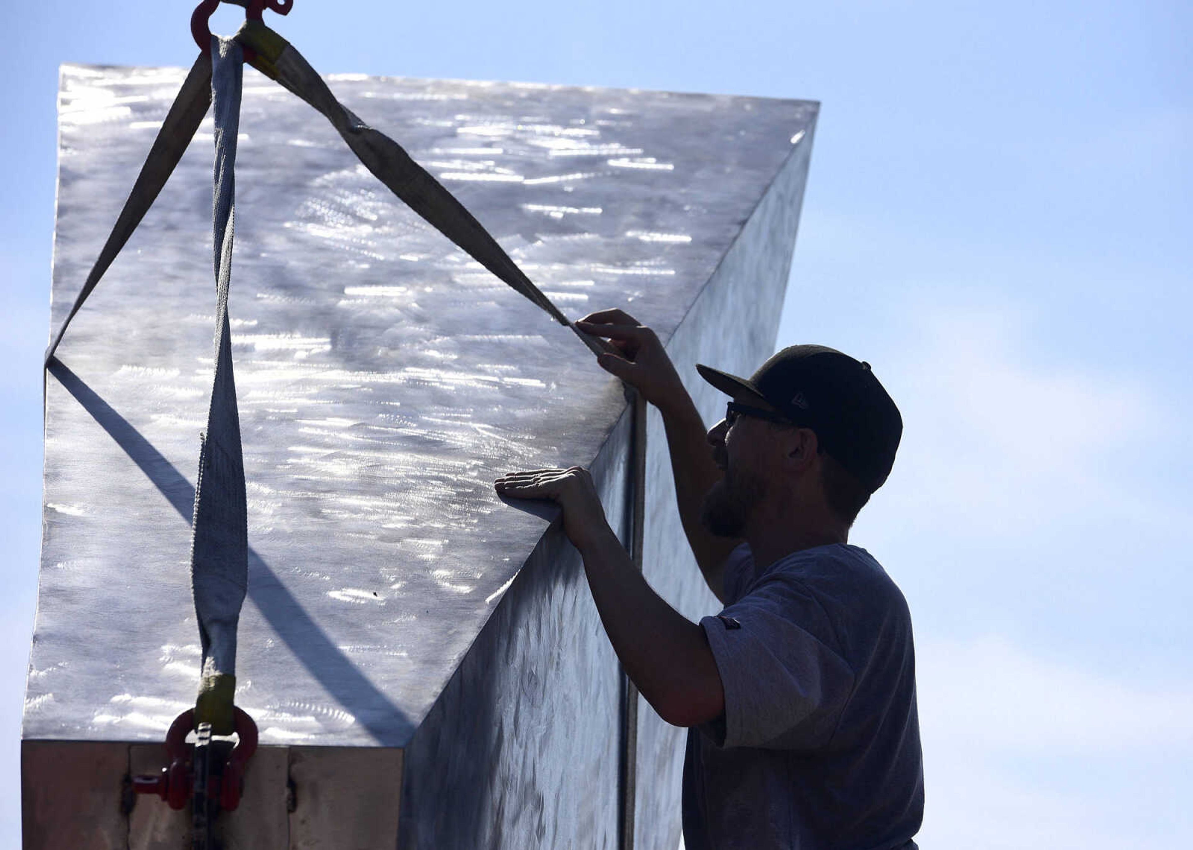 Chris Wubbena adjusts the straps around a section of his 14-foot sculpture, "Commence" to lift for installation in the Fountain Street roundabout on Monday, July 24, 2017, near the River Campus in Cape Girardeau.