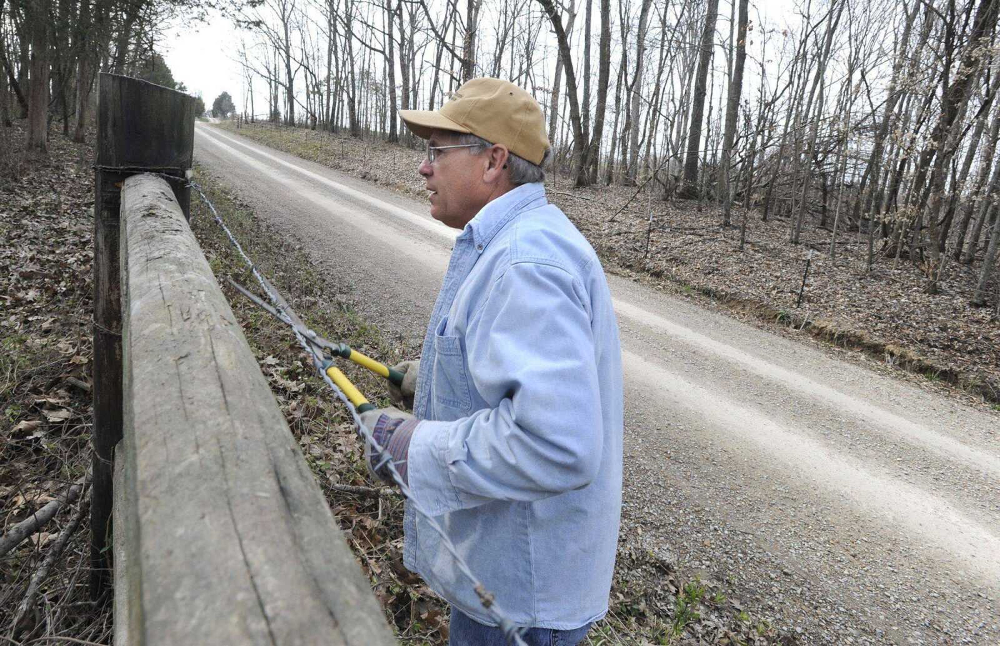 Dennis Winkler performs fence maintenance Friday on property he owns along a graveled stretch of Perry County Road 540 near Biehle, Mo. Perry County relies on a three-eighths sales tax to pay for improvements and maintenance on its 480 miles of county roads, but the tax will expire Dec. 31 if voters opt not to renew it April 6. (Fred Lynch)