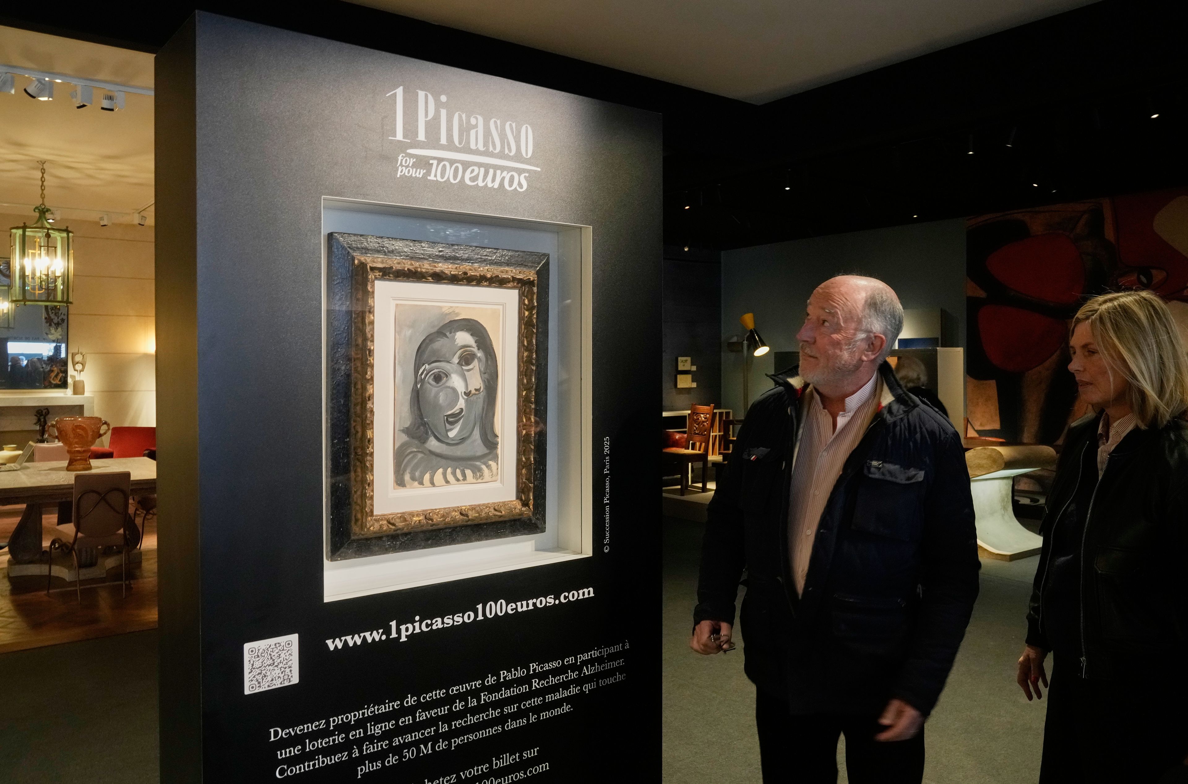People look at the Head of a Woman by Pablo Picasso, painted in 1941, in Paris, Friday, April 10, 2026, ahead of a lottery in which the painting is being raffled off to raise money for Alzheimer’s research (AP Photo/Michel Euler)
