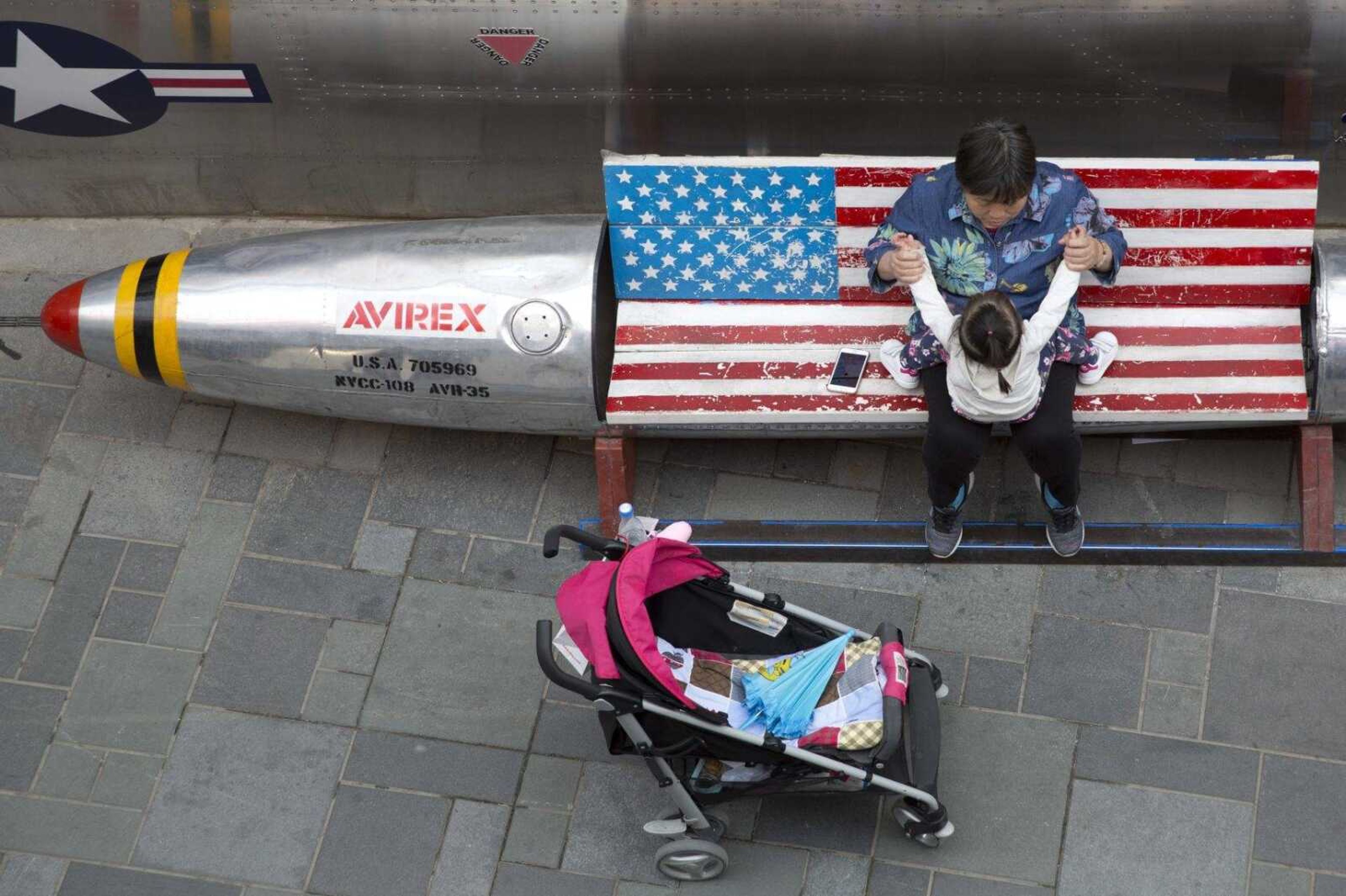 A woman tends to a child near a promotional gimmick in the form of a bomb and the U.S. flag outside a U.S. apparel shop in Beijing. China's options to retaliate in an escalating trade dispute with Washington go beyond matching U.S. tariff hikes to targeting American companies and government debt.