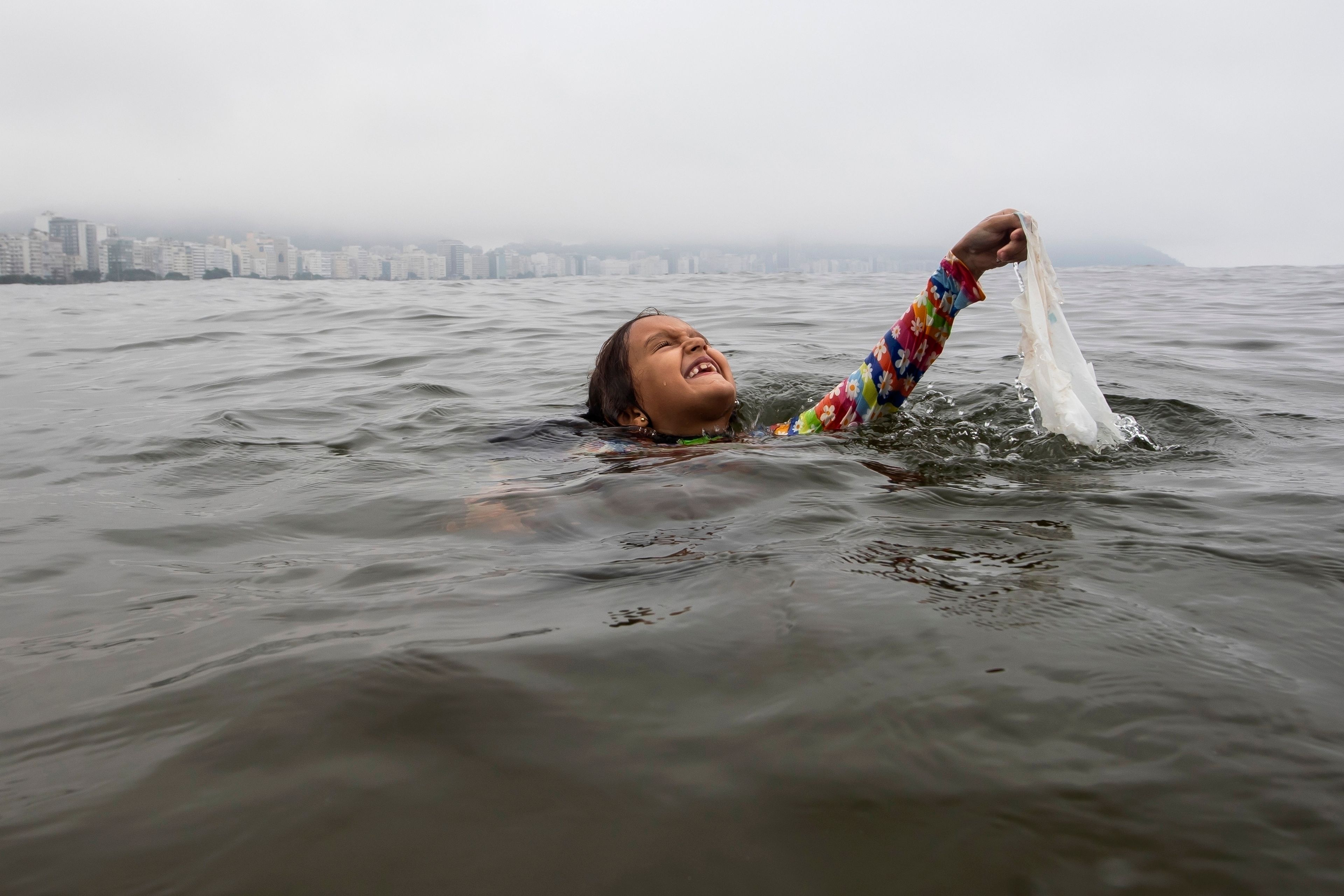 FILE- Nina Gomes recovers a discarded plastic bag from ocean waters, near Copacabana beach in Rio de Janeiro, Brazil, March 19, 2024. (AP Photo/Bruna Prado, File)