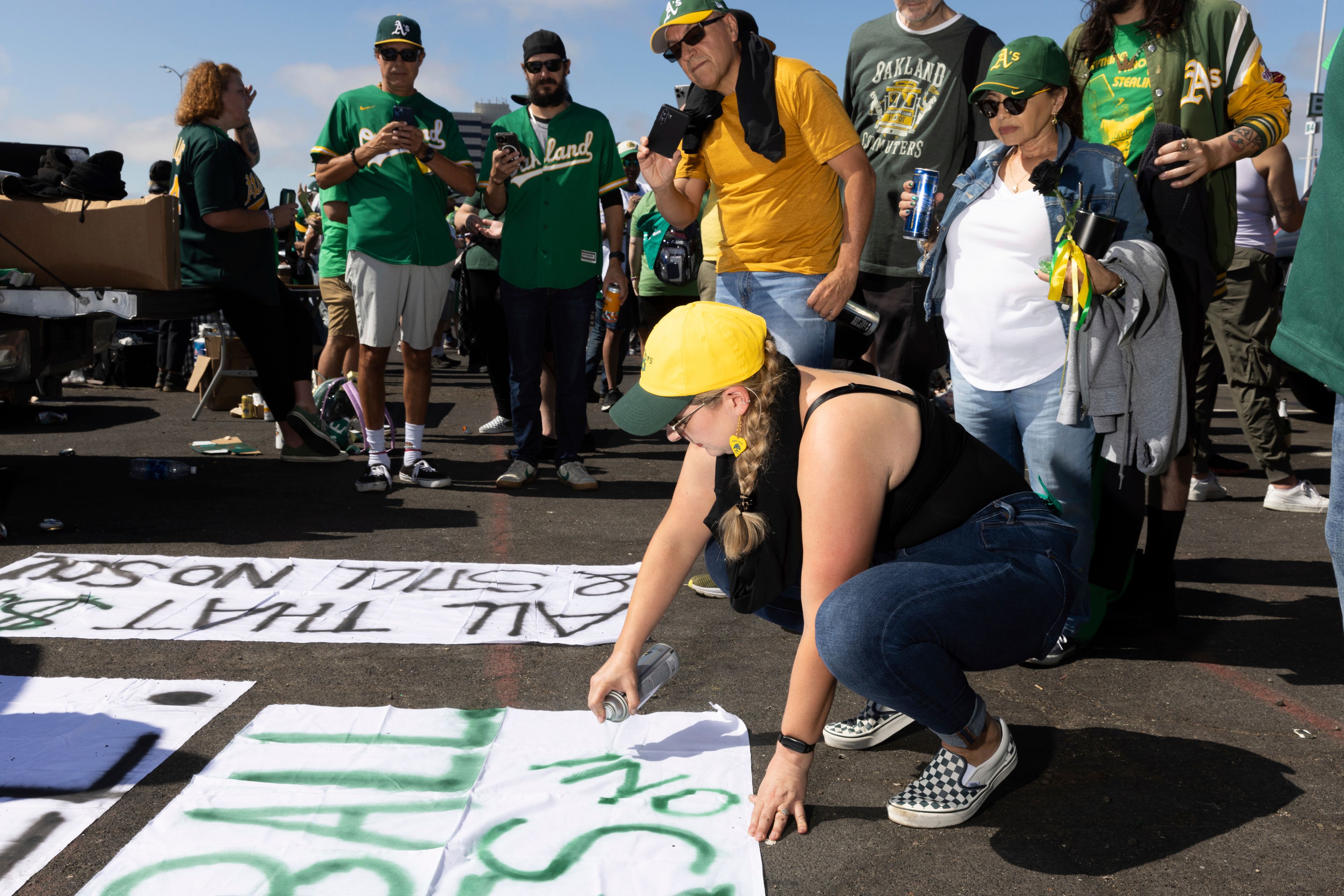 Michelle Leon paints a sign outside the Oakland Coliseum before a baseball game between the Oakland Athletics and the Texas Rangers Thursday, Sept. 26, 2024, in Oakland, Calif. (AP Photo/Benjamin Fanjoy)