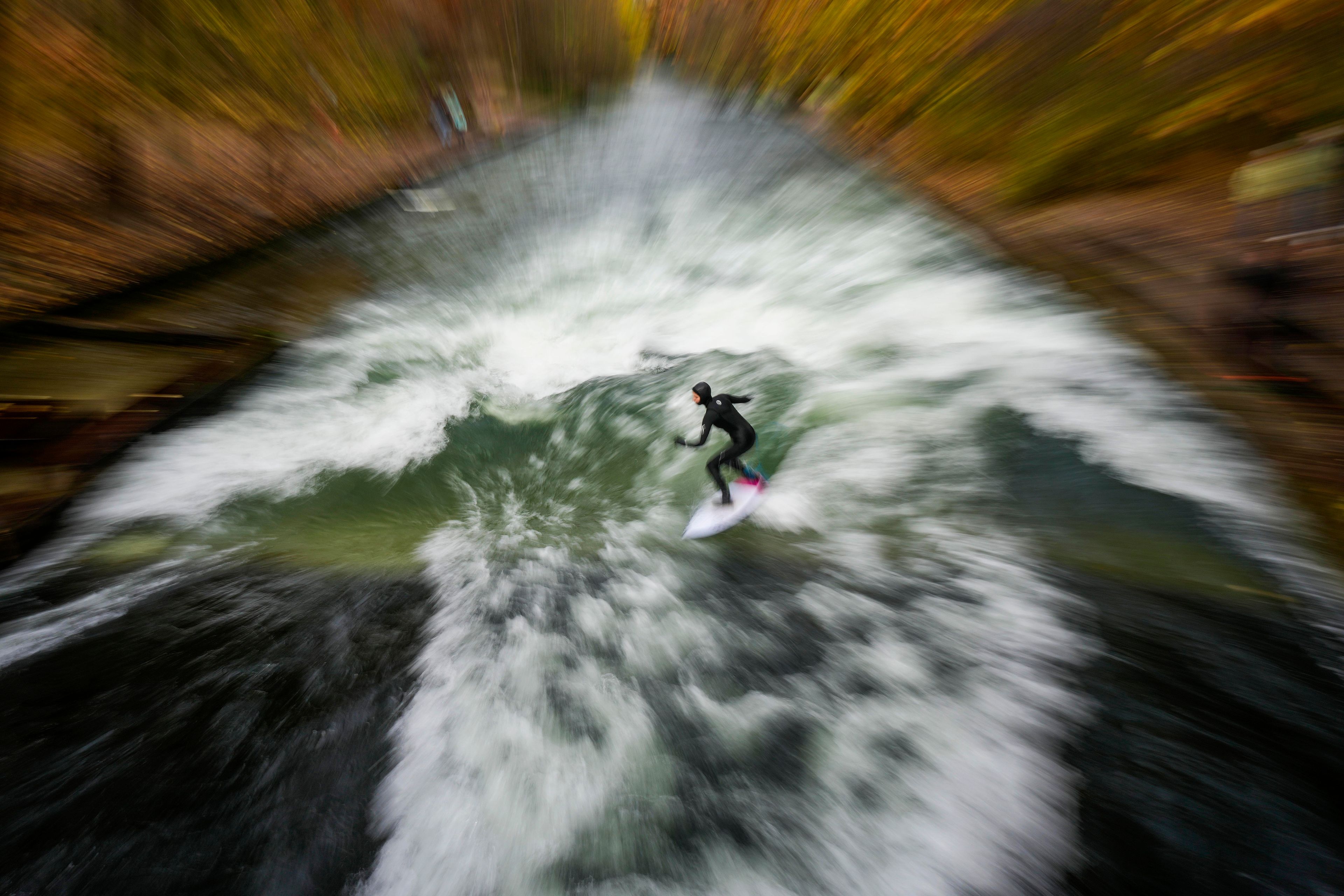 A surfer rides on an artificial wave in the river 'Eisbach' at the 'Englischer Garten' (English Garden) downtown in Munich, Germany, Monday, Nov. 11, 2024. (AP Photo/Matthias Schrader)