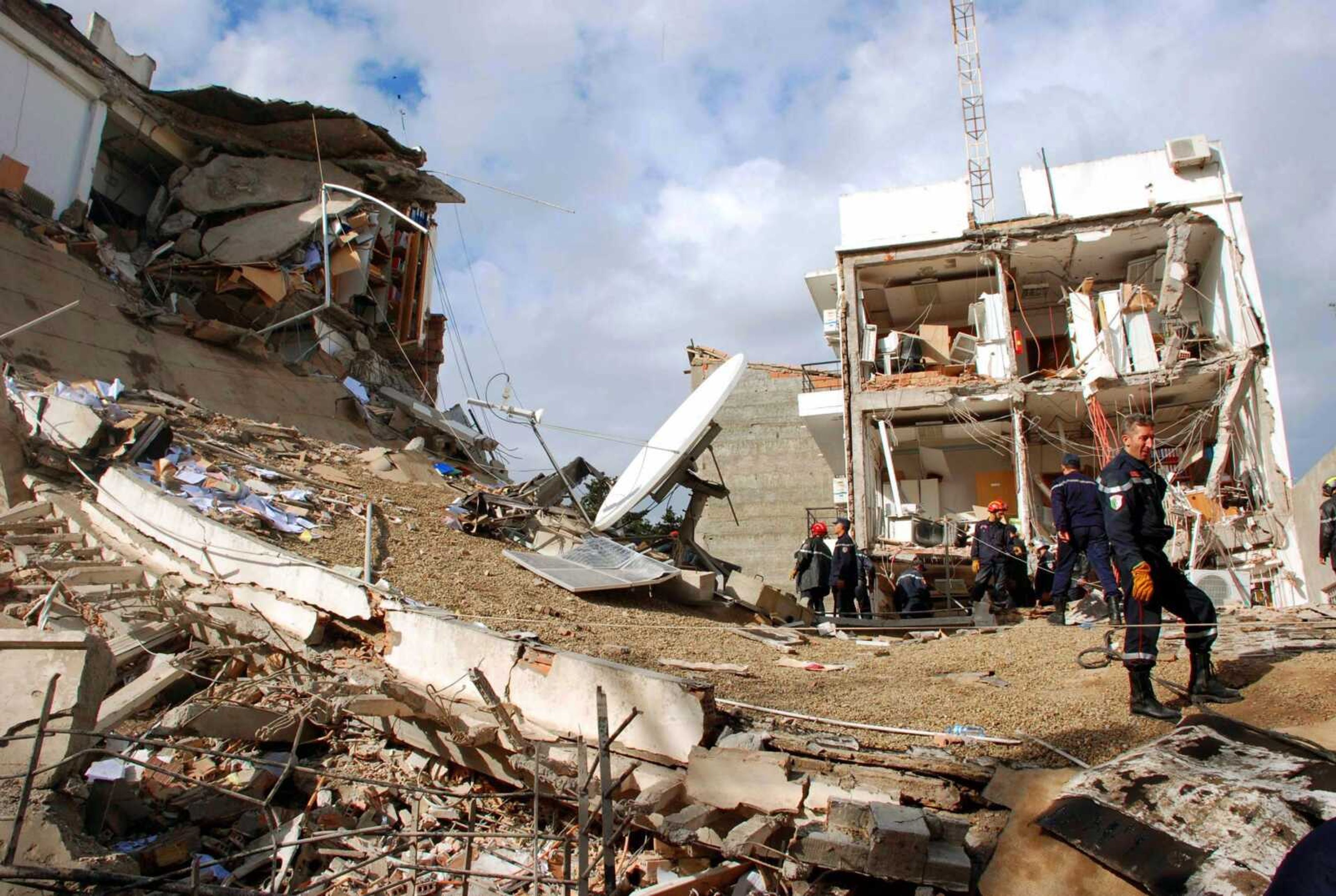 Rescuers worked Tuesday at the site of a bomb blast in Algiers, Algeria. Car bomb attacks targeting United Nations offices and a government council killed at least 26 people and injured dozens of others in Algeria's capital Tuesday, authorities said. At least 12 U.N. staff members were missing. (Associated Press)