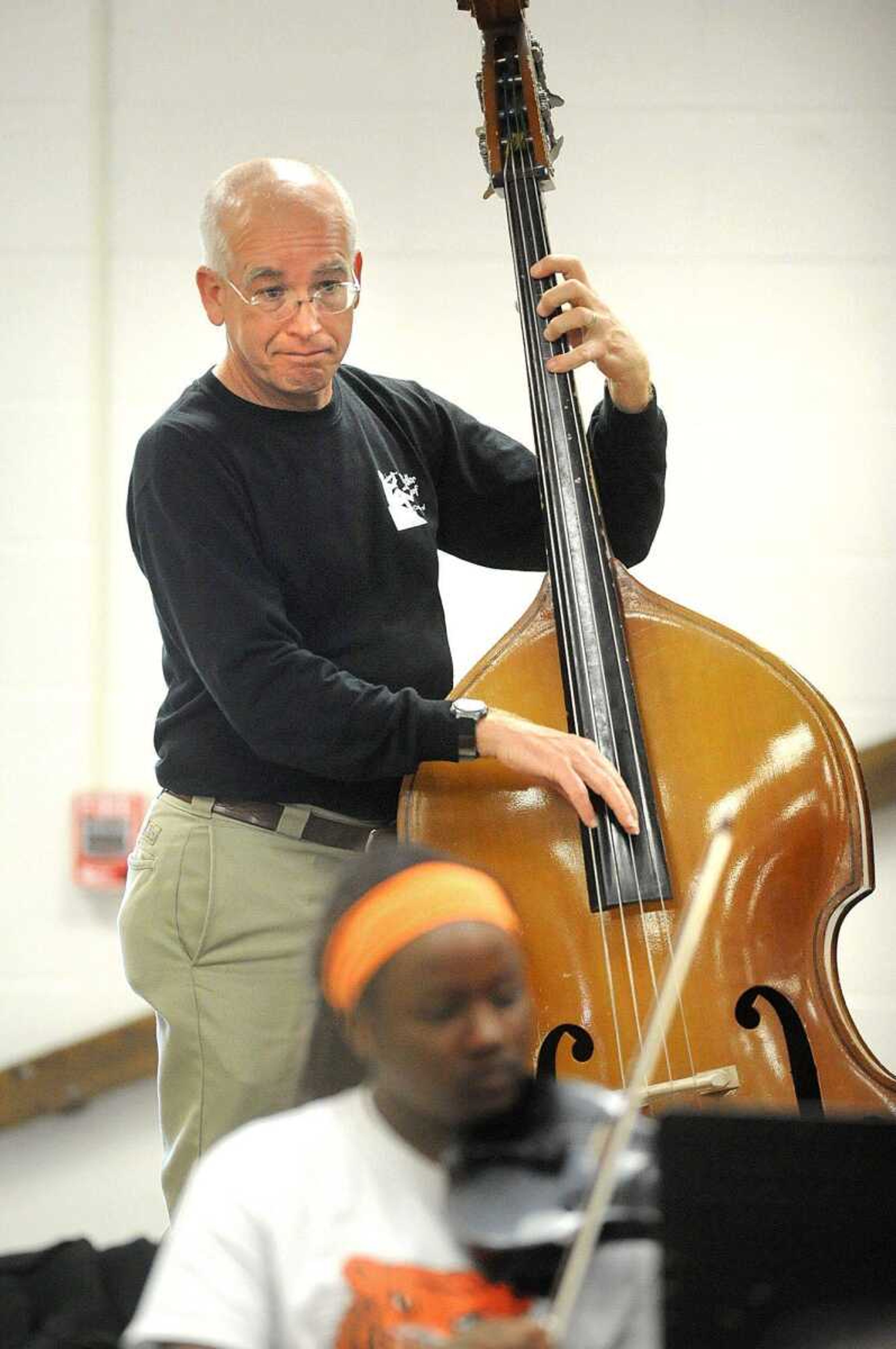 Steve Schaffner strums an upright bass while a student warms up Monday at Cape Girardeau Central Junior High School. More pictures are in a gallery at <b><i>semissourian.com</i></b>. (Laura Simon)