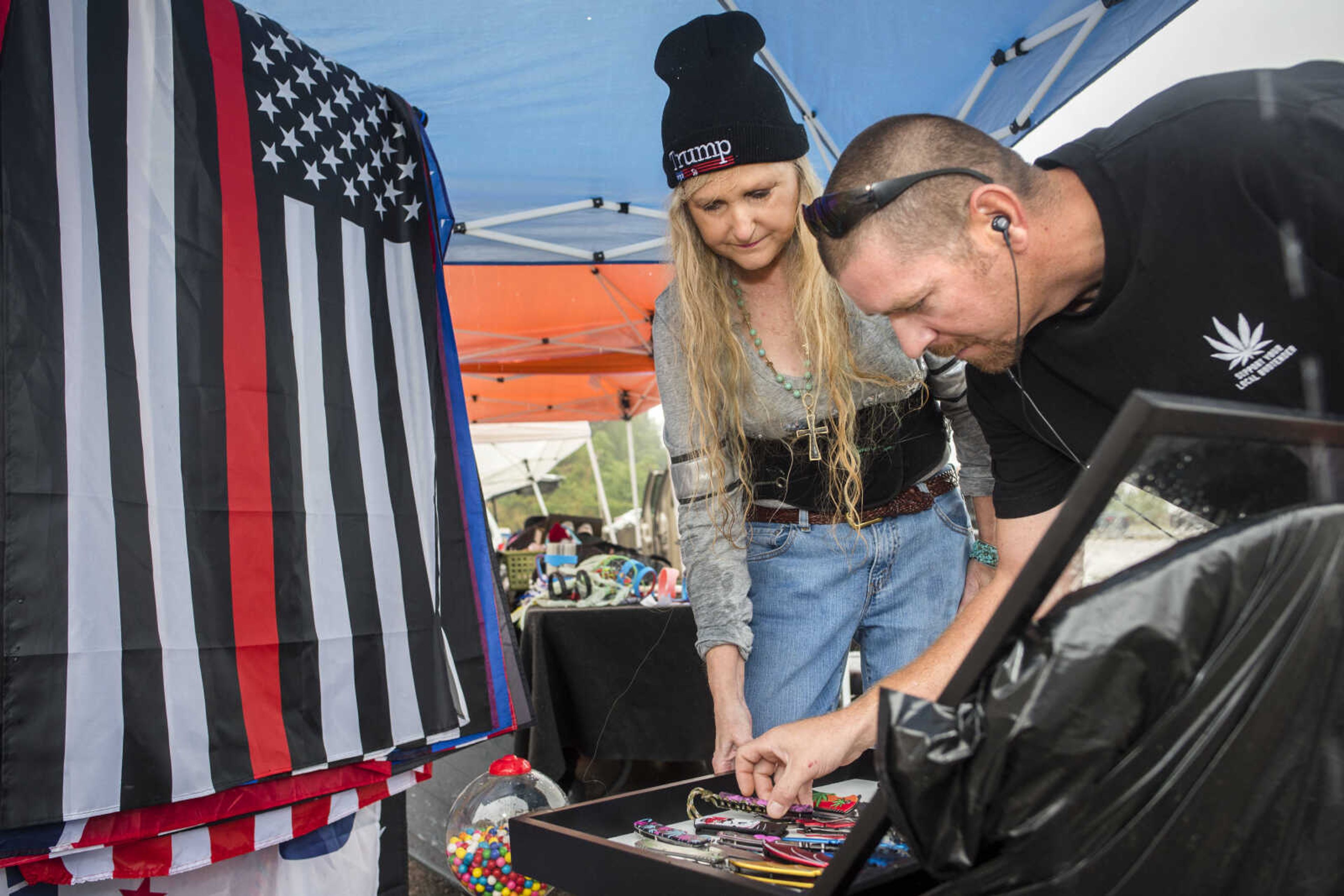 Poplar Bluff vendor Jennifer House, center right, shows a selection of knives to her final customer of the day, Cape Girardeau resident Nate Malone, far right, while packing up her stand with Gary House (not pictured) on Sunday, Oct. 6, 2019, at the Cape Girardeau Downtown Tailgate Flea Market. The Houses were two of the last vendors open for business after afternoon rains caused an early closure of the market.