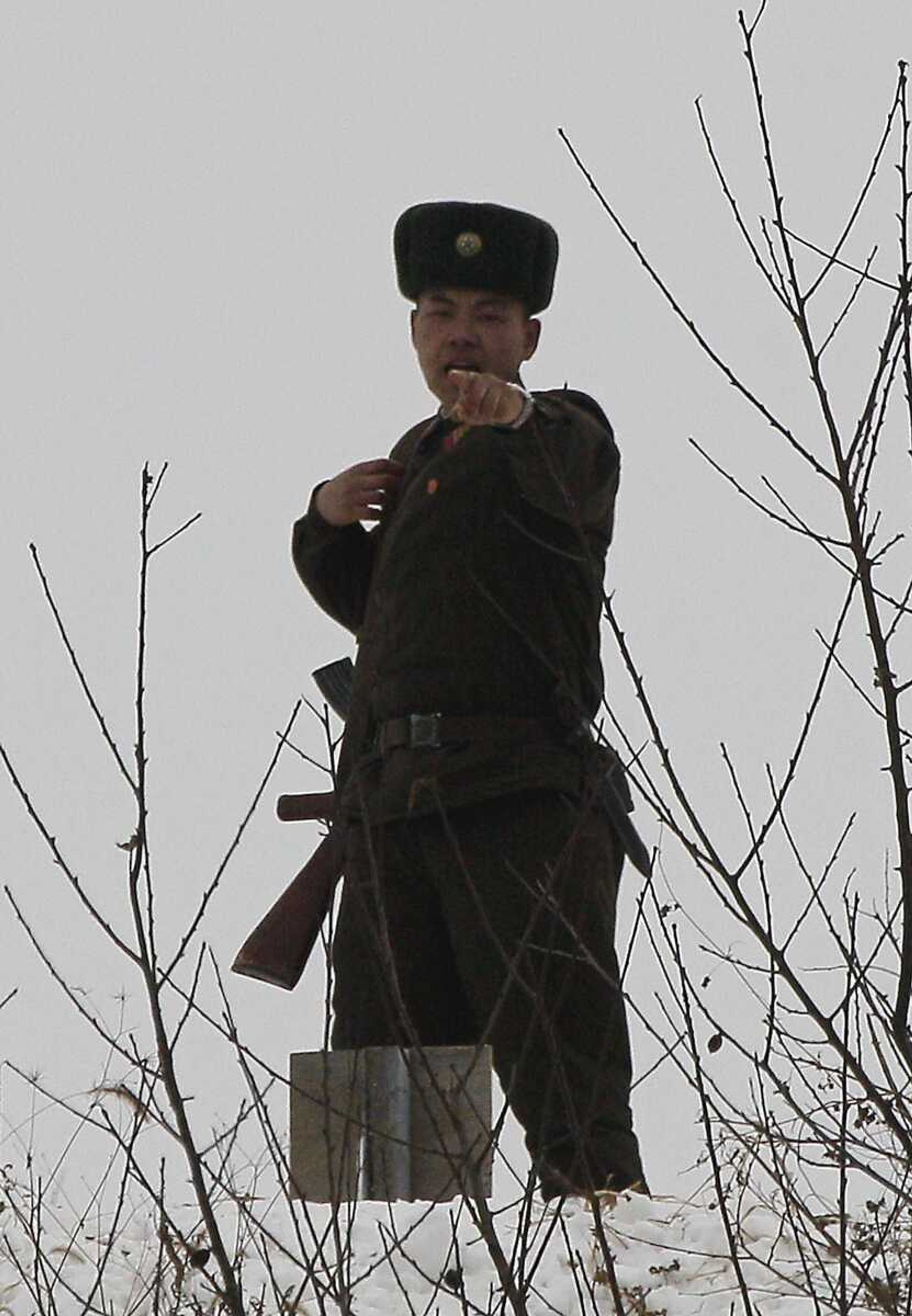 A North Korean soldier gestures towards a passenger boat while he stands guard on a pathway along the bank of the Yalu River, the China-North Korea border river, near North Korea's town of Sinuiju, opposite to the Chinese border city of Dandong, Sunday Nov. 28, 2010. (AP Photo/Andy Wong)