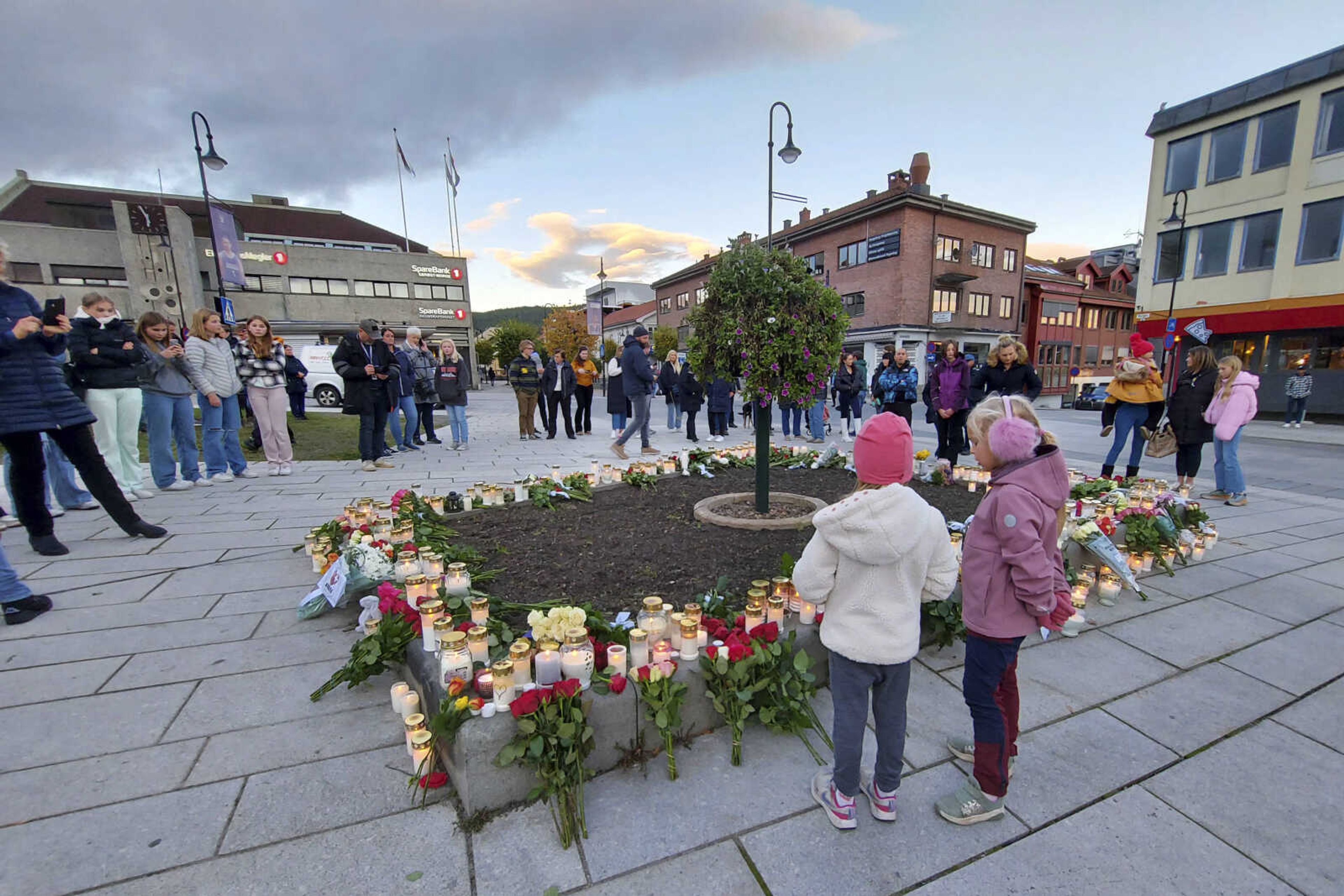 People gather around flowers and candles Thursday, Oct. 14, 2021, after a man killed several people Wednesday afternoon in Kongsberg, Norway.