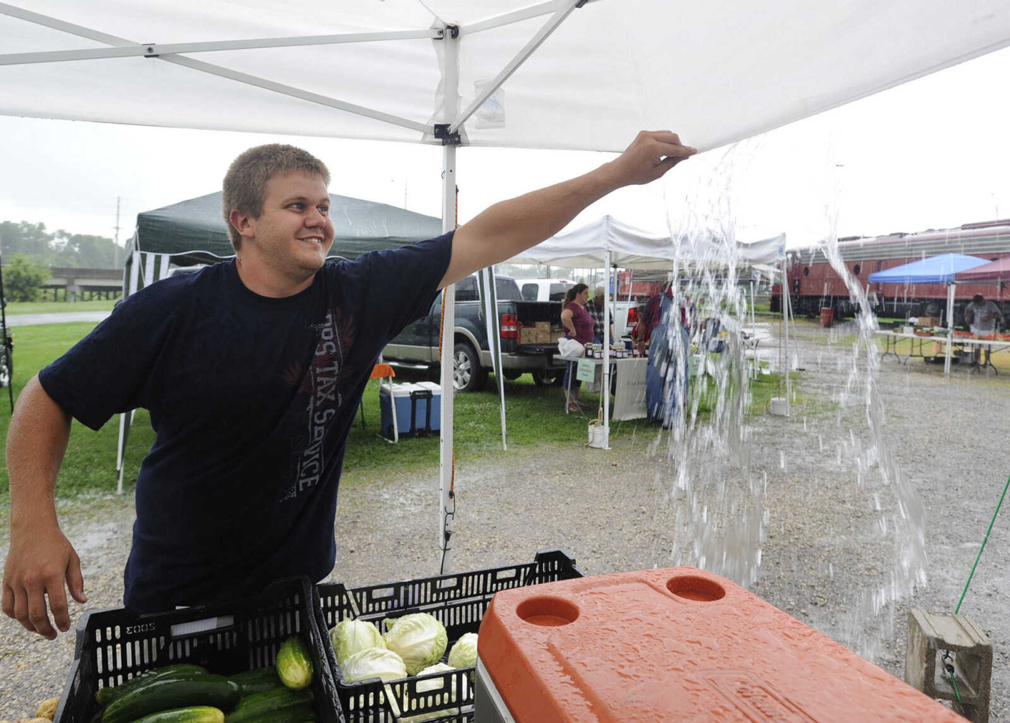 Lance Menard of St. Mary, Missouri releases rainwater above his stand Tuesday, July 7, 2015 at the Jackson Farmer's Market in Jackson.