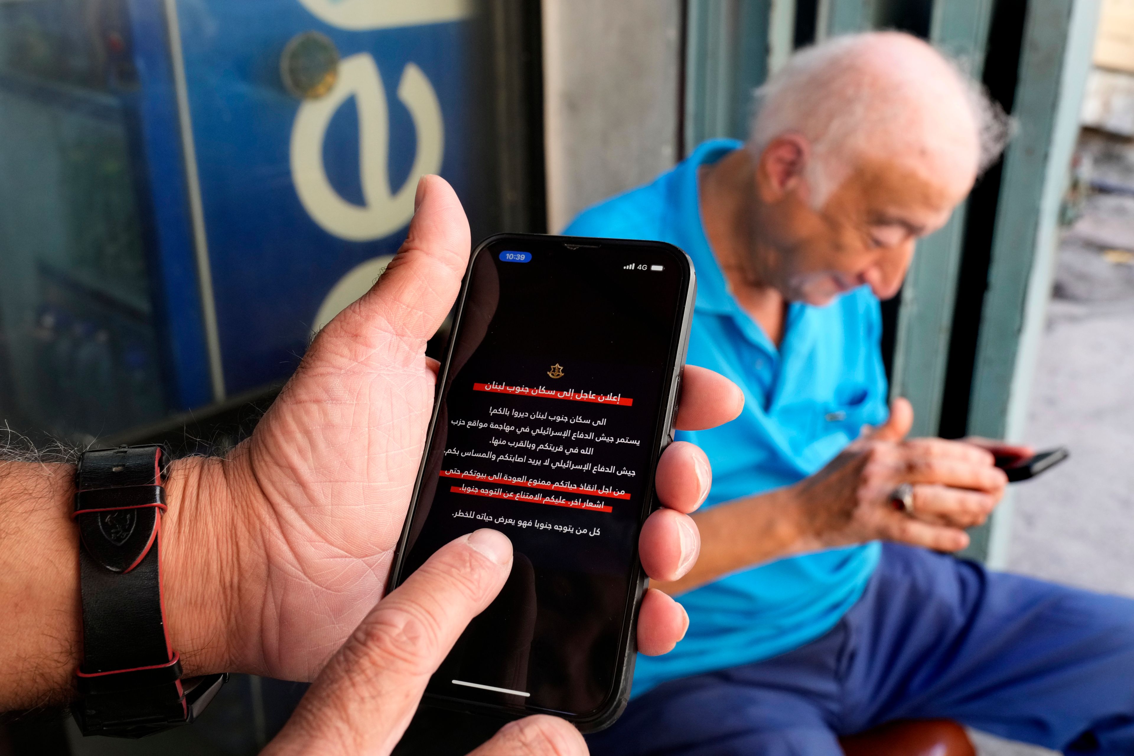 Men read mobile phone alerts telling residents of southern Lebanon not to return to their homes until further notice because of operations Israel says are targeting Hezbollah facilities in Beirut, Lebanon, Wednesday, Oct. 9, 2024. (AP Photo/Hussein Malla)