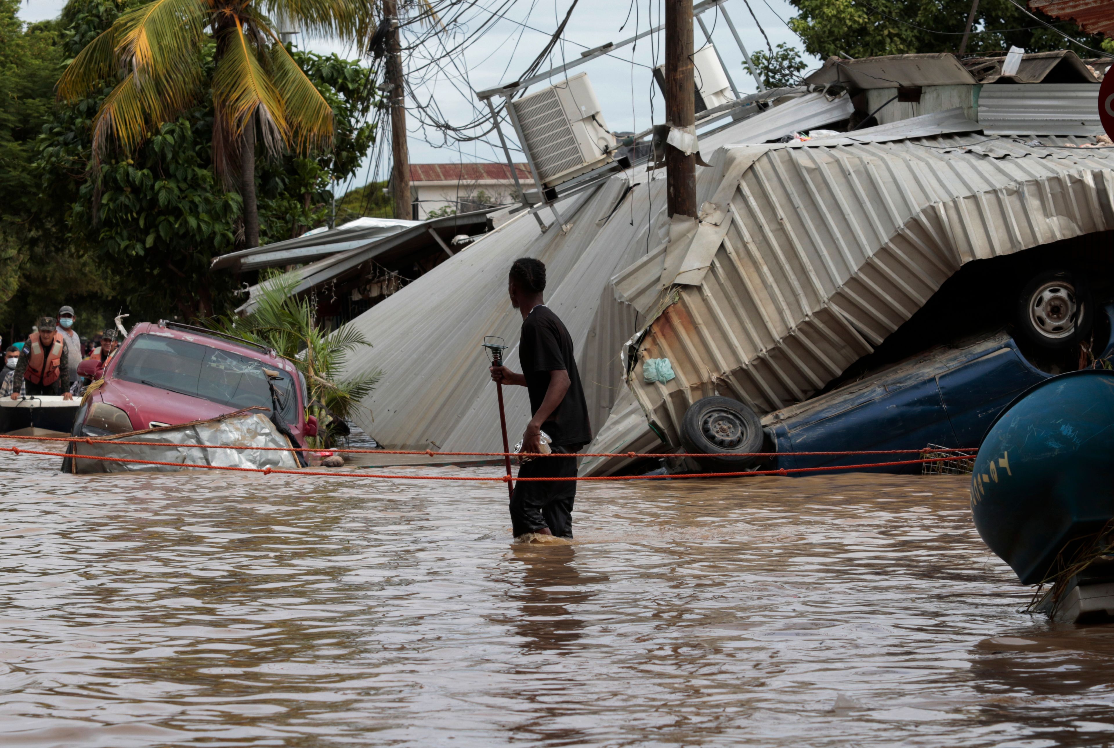 FILE - A resident walking through a flooded street looks back at storm damage caused by Hurricane Eta in Planeta, Honduras, Nov. 6, 2020. (AP Photo/Delmer Martinez, File)