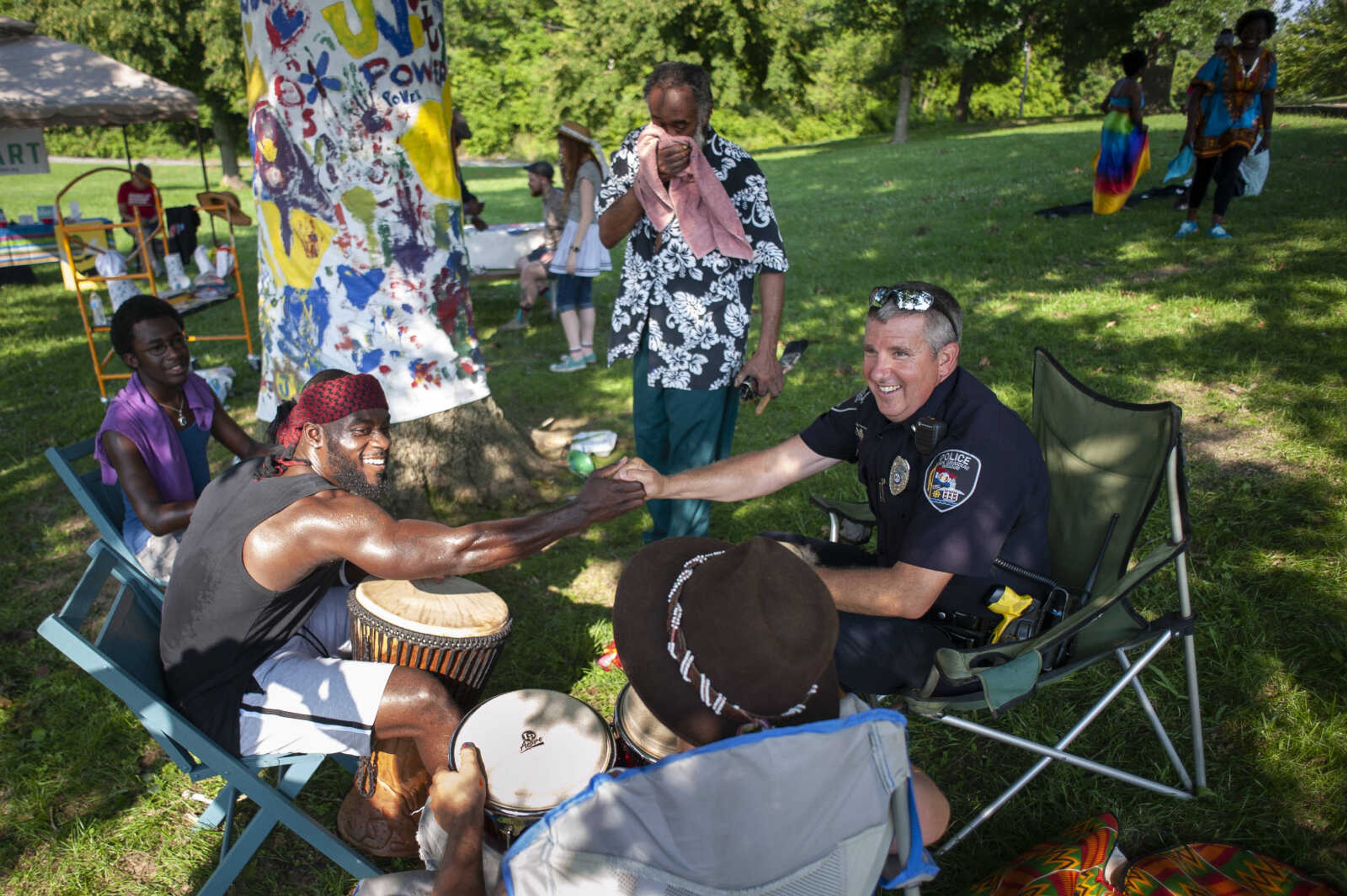 Kweku Arkorful, originally of Ghana and now Cape Girardeau, shakes hands with Cape Girardeau Police Lt. Bradley Smith after both took part in a drum circle next to other drum circle participants including Montell Jackson, 17, of Watertown, New York, (left), Bankole Agbon, originally of Milwaukee and now Jackson (standing) and Ben Koller, originally of Milwaukee and now Asheville, North Carolina, (foreground) during a Cape Girardeau Community Art Day on Sunday, June 30, 2019, at Ranney Park in Cape Girardeau.&nbsp;