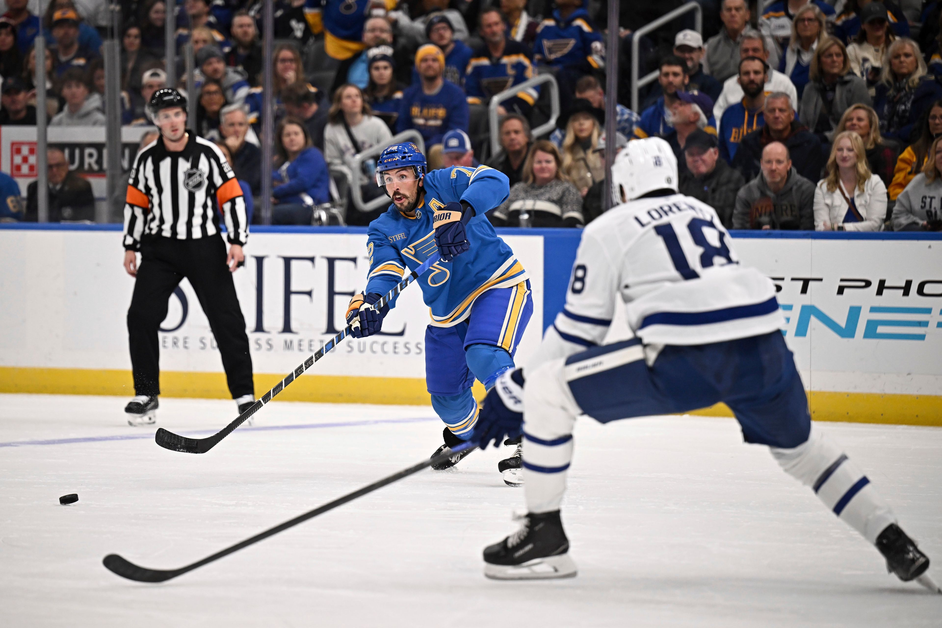 St. Louis Blues' Justin Faulk, center, passes the puck as Toronto Maple Leafs' Steven Lorentz (18) defends during the second period of an NHL hockey game Saturday, Nov. 2, 2024, in St. Louis. (AP Photo/Connor Hamilton)