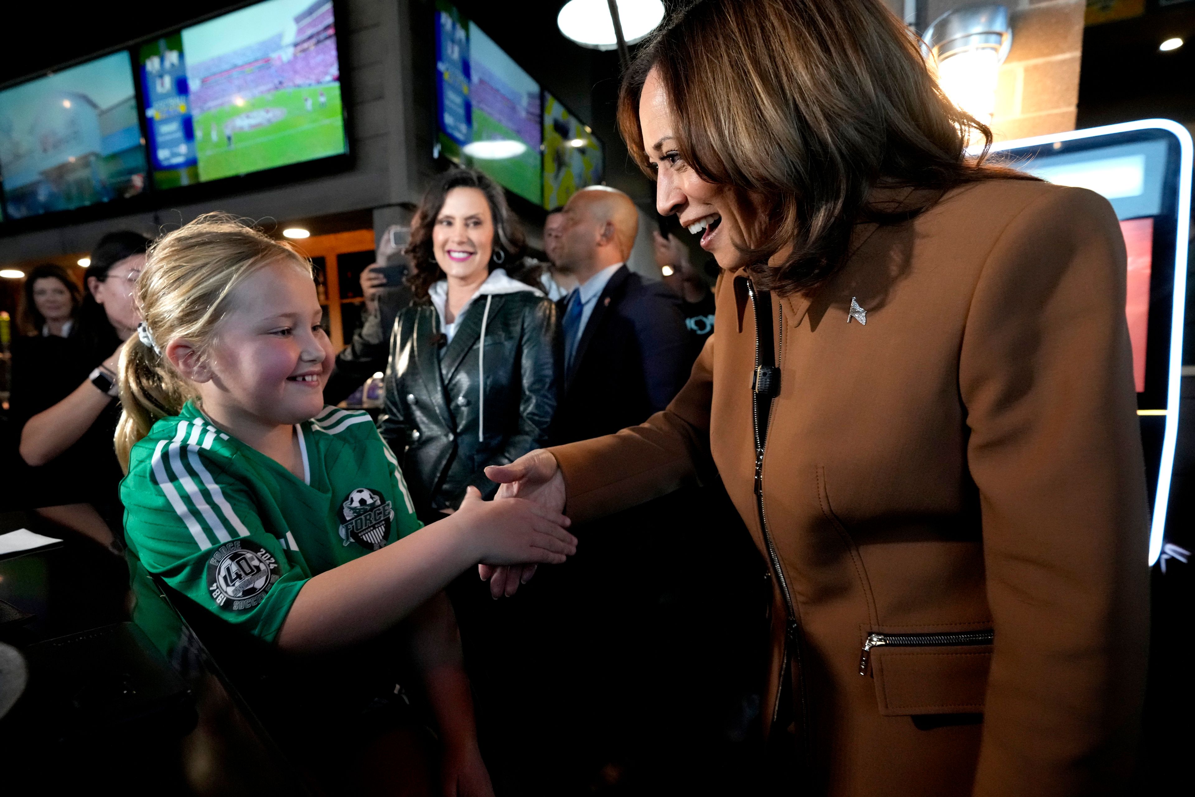 Democratic presidential nominee Vice President Kamala Harris, from right, and Michigan Gov. Gretchen Whitmer greet a young customer at the Trak Houz Bar & Grill after a campaign rally in Kalamazoo, Mich. (AP Photo/Jacquelyn Martin)