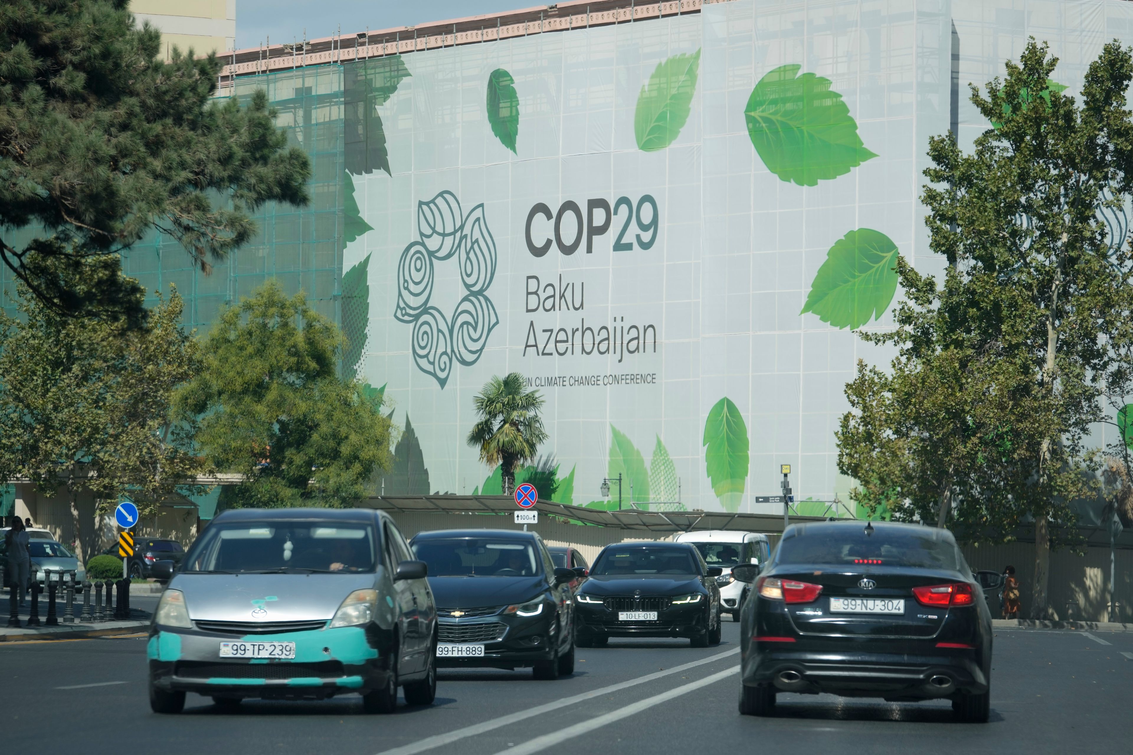 Vehicles drive near a sign for COP29, the United Nations Climate Change Conference, in Baku, Azerbaijan, Monday, Sept. 16, 2024. (AP Photo/Sergei Grits)