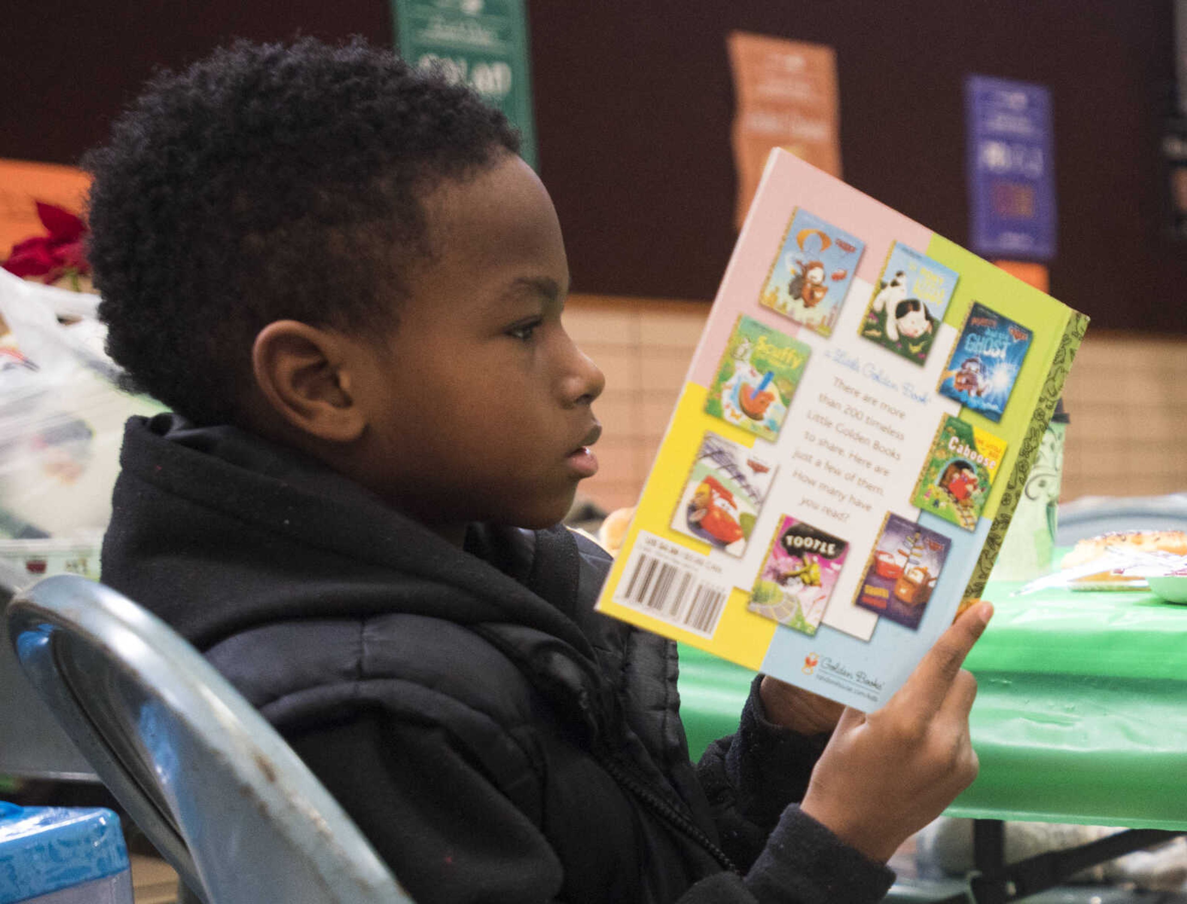 Todd Blissett, 6, reads a new book during a free lunch hosted by Student Santas on Dec. 25, 2017, at Jefferson Elementary School in Cape Girardeau.