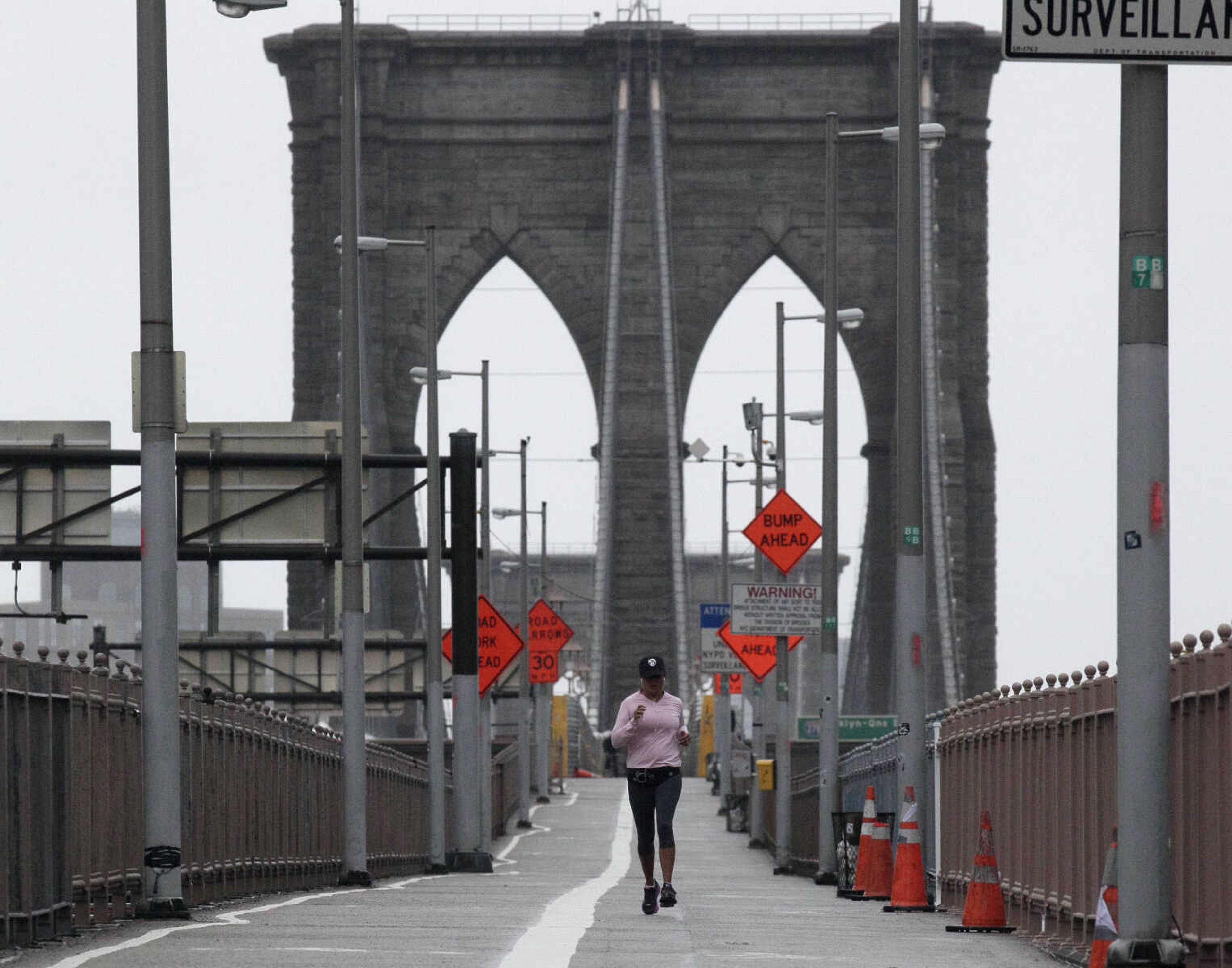 A woman jogs across the Brooklyn Bridge, in New York,  Monday, Oct. 29, 2012. Hurricane Sandy continued on its path Monday, as the storm forced the shutdown of mass transit, schools and financial markets, sending coastal residents fleeing, and threatening a dangerous mix of high winds and soaking rain.  (AP Photo/Richard Drew)