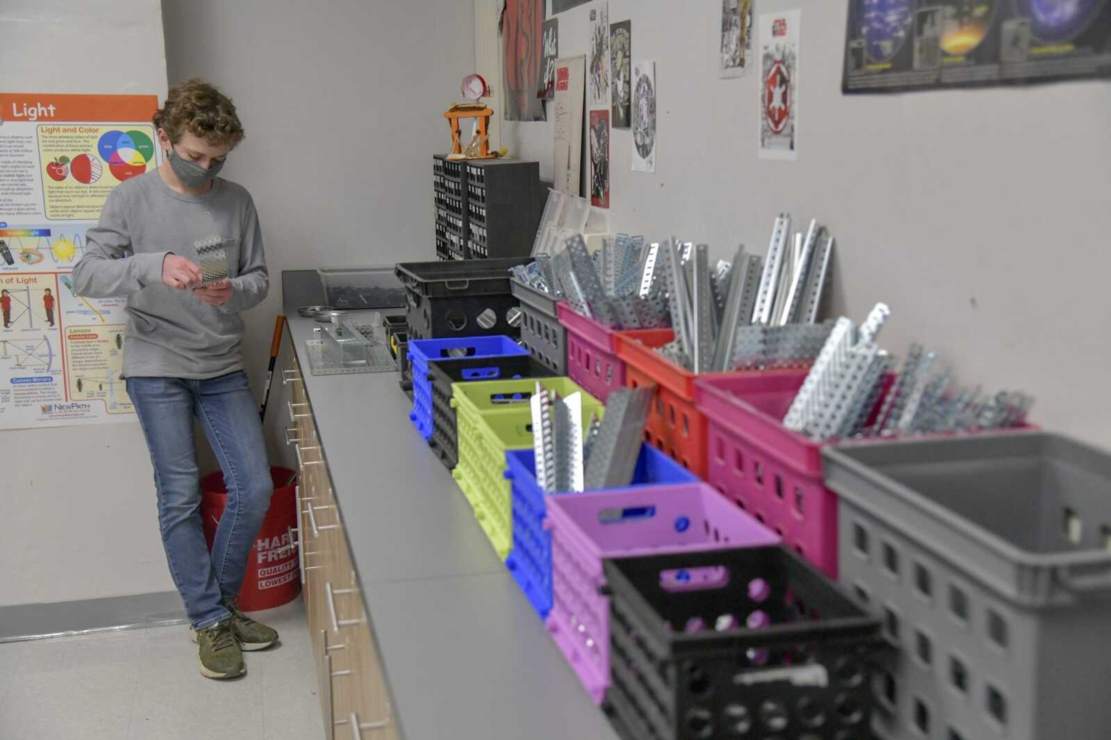 Ninth grader at Cape Central High School and mentor to the TigerTech Gibson Curtis assembles an addition to the robot from materials he collected from Mrs. West's supplies, seen right, on Monday, March 22, 2021.