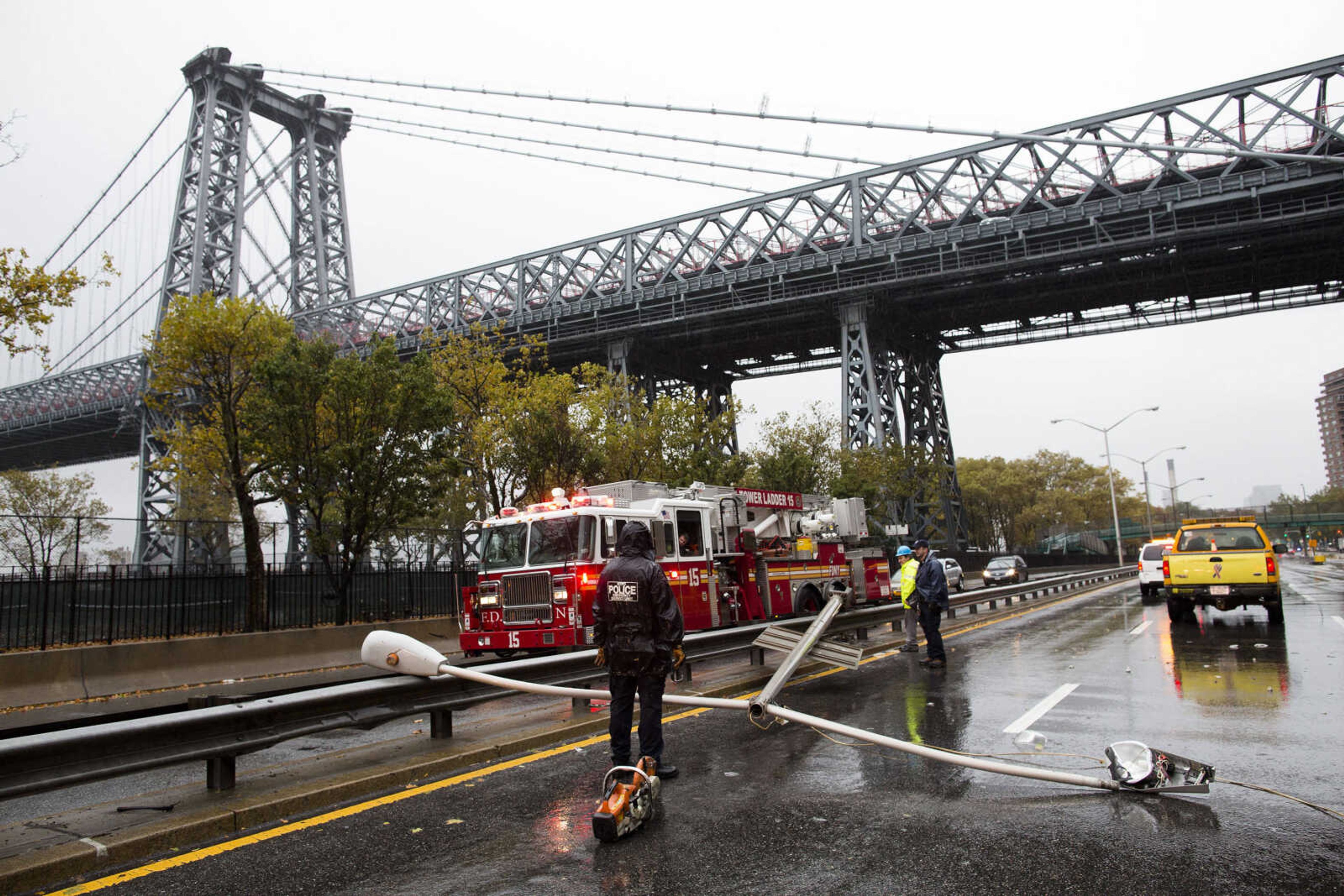 Police and firefighters respond to a downed street light on FDR drive, Monday, Oct. 29, 2012, in New York. Hurricane Sandy continued on its path Monday, forcing the shutdown of mass transit, schools and financial markets, sending coastal residents fleeing, and threatening a dangerous mix of high winds and soaking rain.  (AP Photo/Mel Evans)